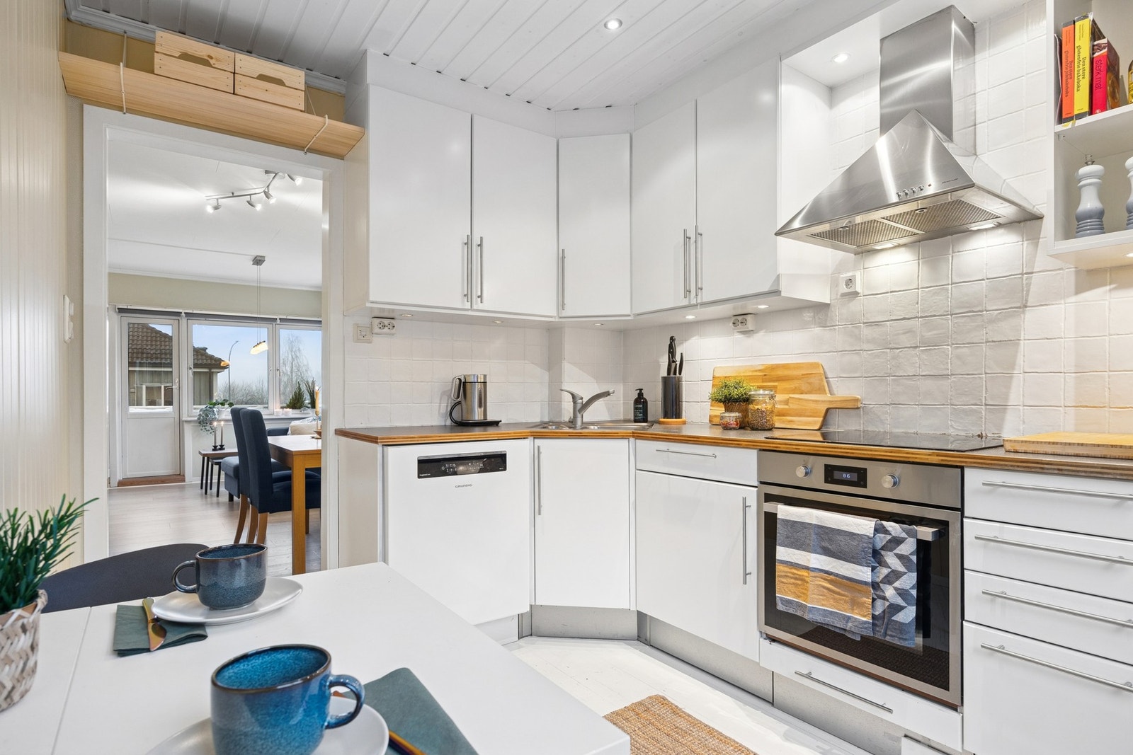 De lyse overflatene, kombinert med fliser mellom benk og overskap og parkett på gulv, gir kjøkkenet et ryddig og tidløst uttrykk. Galleribilde