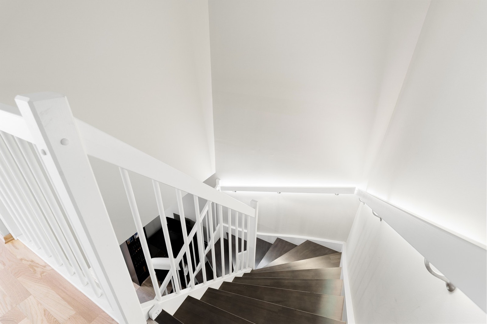 En elegant trapp leder ned til sokkeletasjen, med stilfull LED-belysning langs håndløperen som gir et moderne og eksklusivt preg. Galleribilde