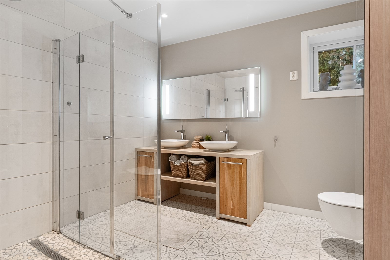 Baderommet i denne etasjen består av et håndlaget servantskap i massiv eik med oppbevaring, stor dusj, to servanter og et vegghengt toalett. Galleribilde