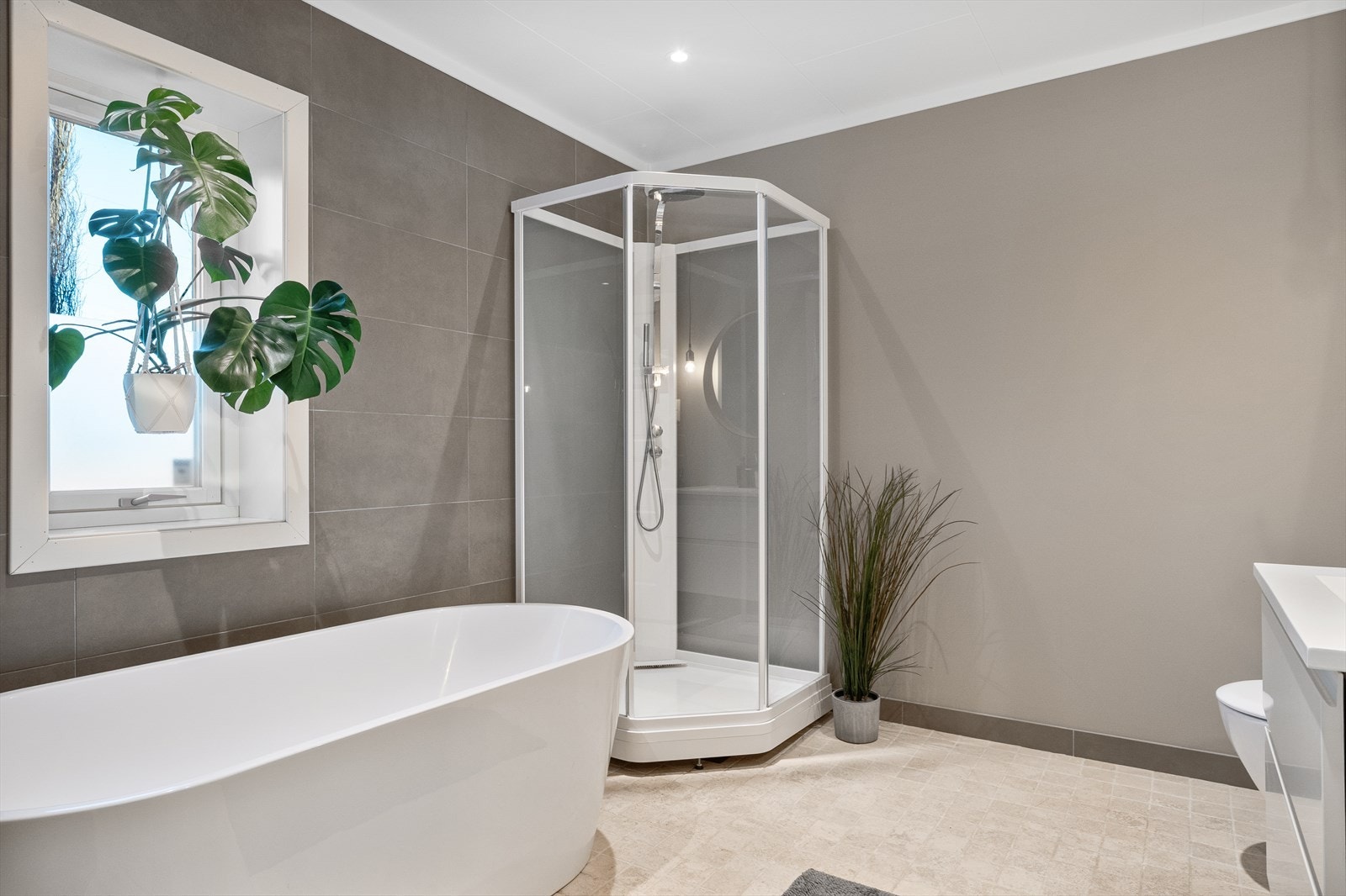 I første etasje ligger også et av boligens to bad. Baderommet har fliser og walls to paint malt med våtromsmaling på veggene og fliser på gulvet med vannbåren varme. Badet er utstyrt med servant, dusjkabinett, badekar og vegghengt toalett. Galleribilde