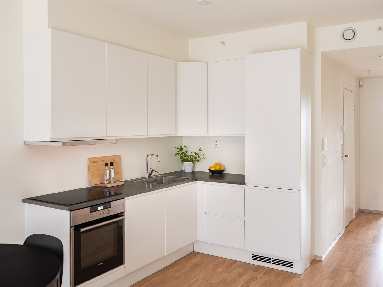 Moderne hjørnekjøkken med integrerte hvitevarer og platetopp. Galleribilde