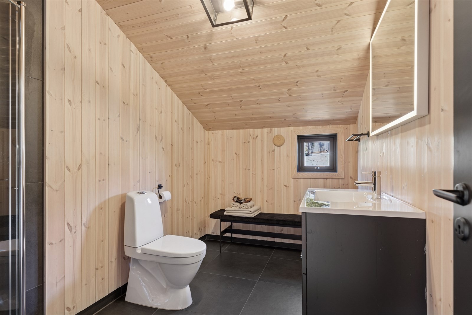 Det er også et bad i 2. etasje, som har samme fine utførelse; mørke fliser på gulv, varmekabler og panel på vegger. Galleribilde