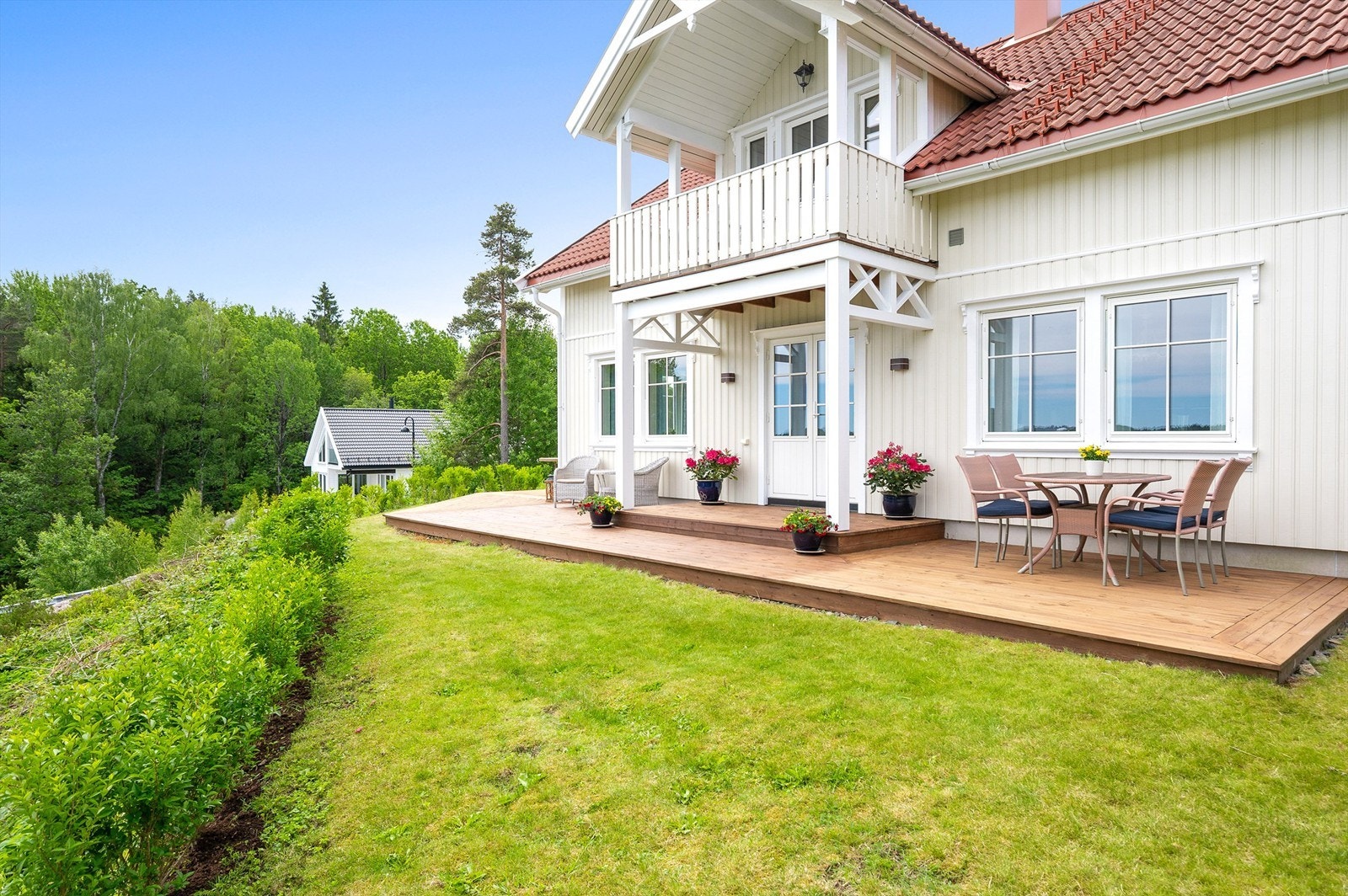 Koselig hage med plen, terrasse, hekk og beplantninger. Galleribilde