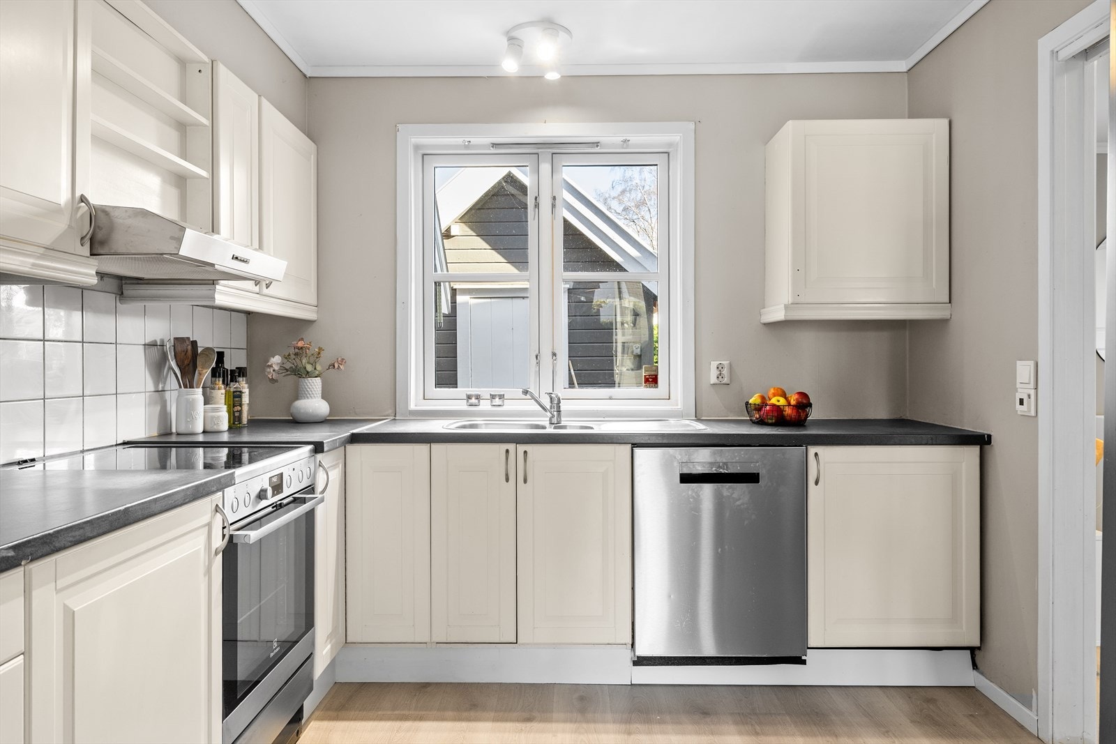 Kjøkkenet er et lyst og innbydende rom som danner et naturlig samlingspunkt i boligen - et sted hvor både hverdag og hygge får utfolde seg. Her er det klassisk kjøkkeninnredning med profilerte fronter, som gir et tidløst og elegant uttrykk. Galleribilde