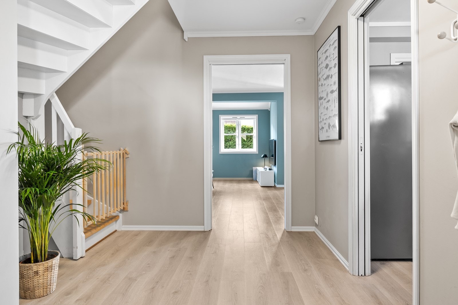 Fra gangen åpner boligen seg opp og leder deg sømløst videre inn mot stuen. Her strømmer dagslyset inn gjennom store vindusflater, og du får et første glimt av den gjennomførte stilen og de harmoniske fargene som preger hele hjemmet. Galleribilde