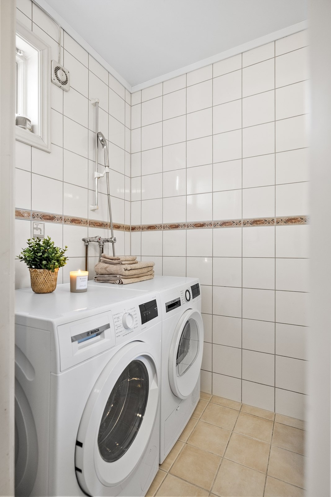 Vaskerommet/WC-rommet fremstår som praktisk og funksjonelt. Her er det fliser på gulvet med elektriske varmekabler, som gir god komfort og en lun følelse under føttene. Veggene er kledd med fliser i lyse fargetoner Galleribilde