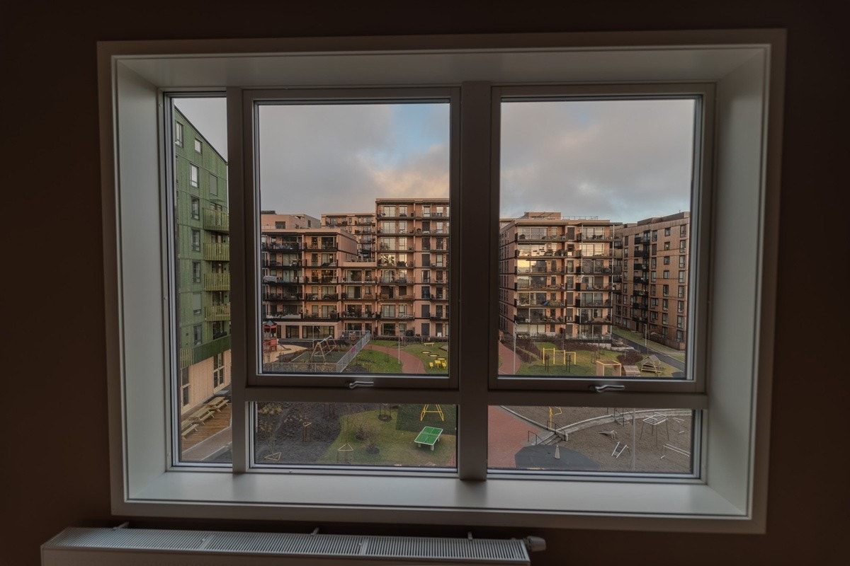 Store vinduer gir rikelig med naturlig lys og utsyn mot grønt gårdsrom Galleribilde