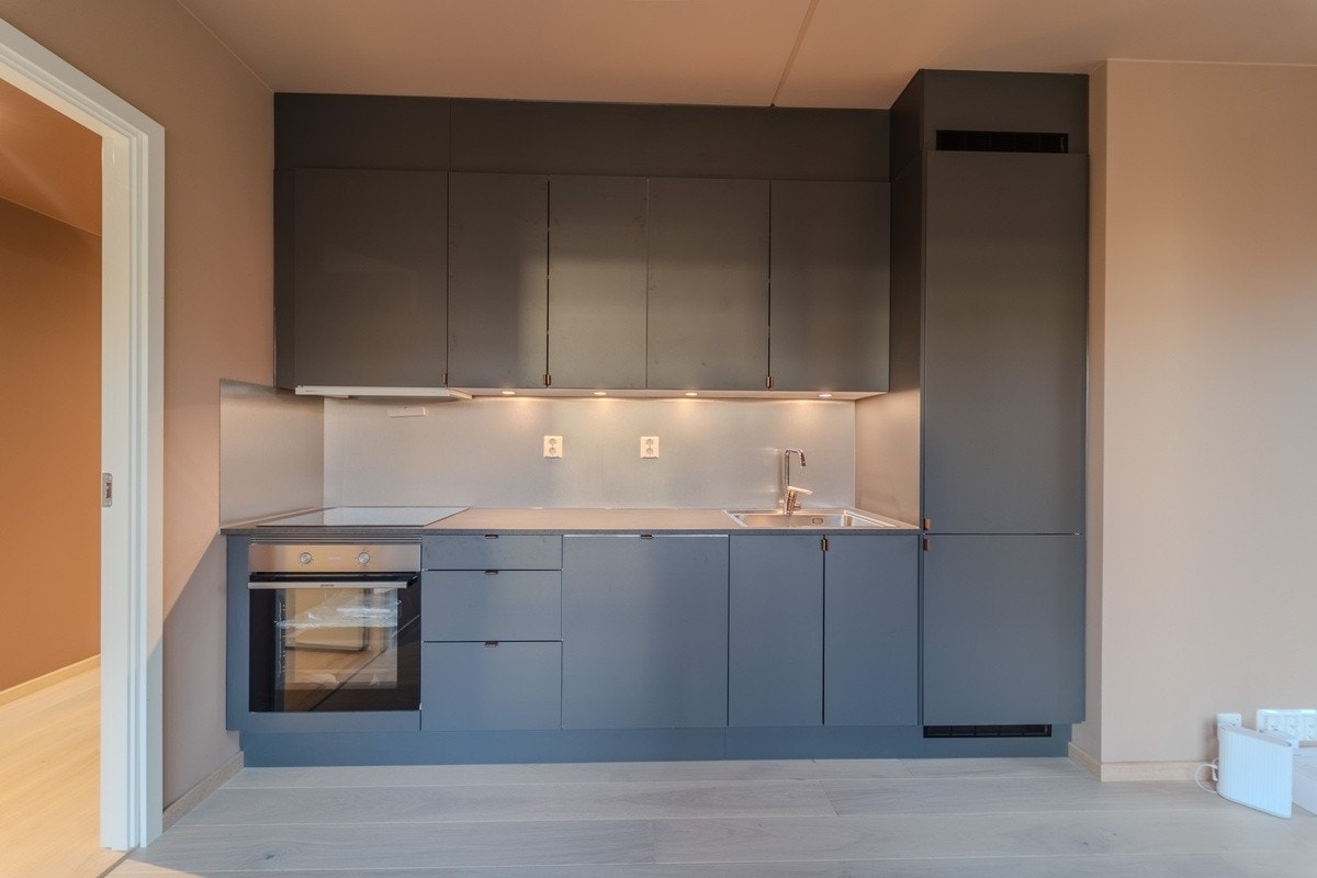 Stilrent kjøkken i mørk utførelse med integrerte hvitevarer Galleribilde