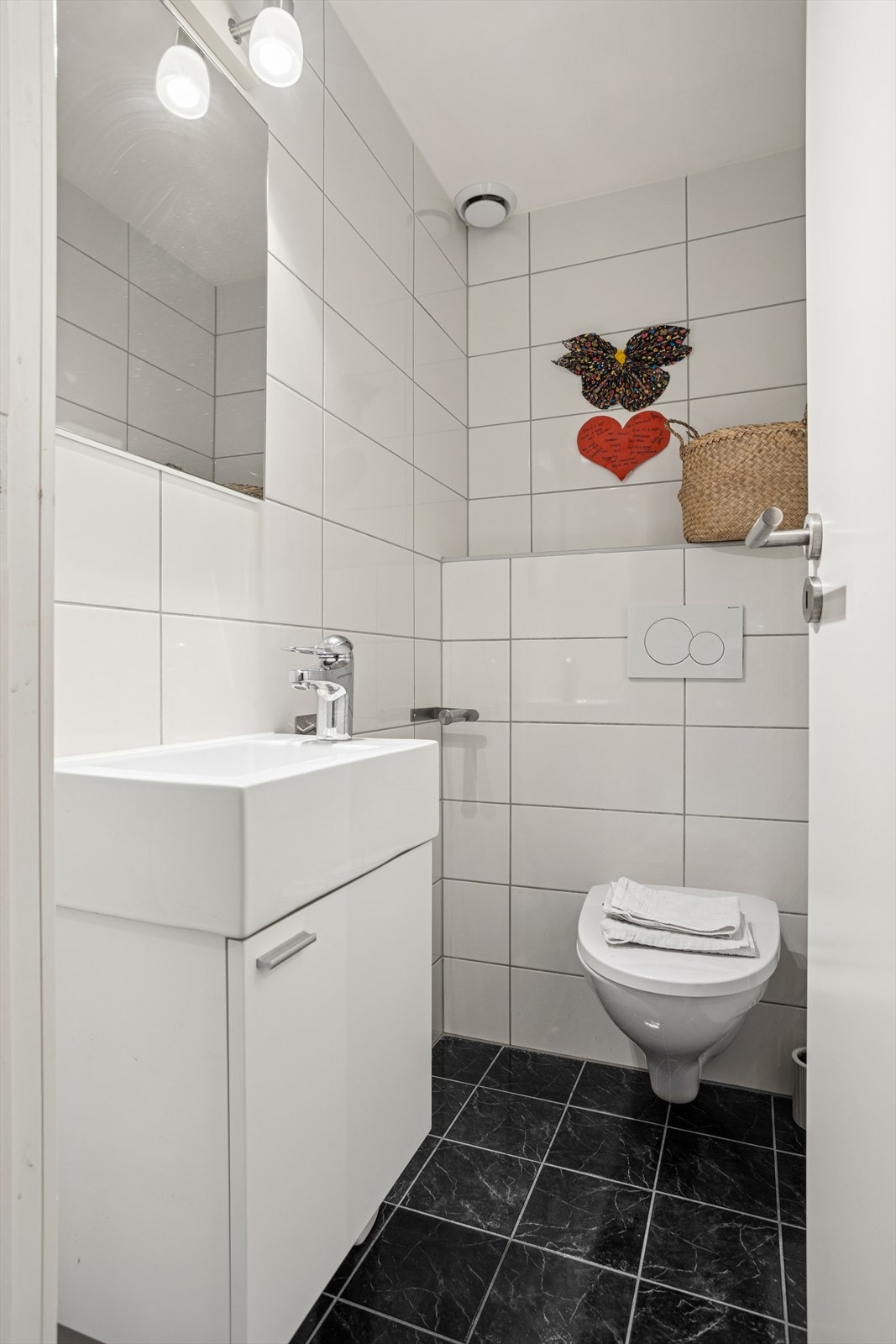 Utrolig praktisk er det med et separat WC. Helfliset, med vegghengt toalett og servant med oppbevaringsplass i skap Galleribilde