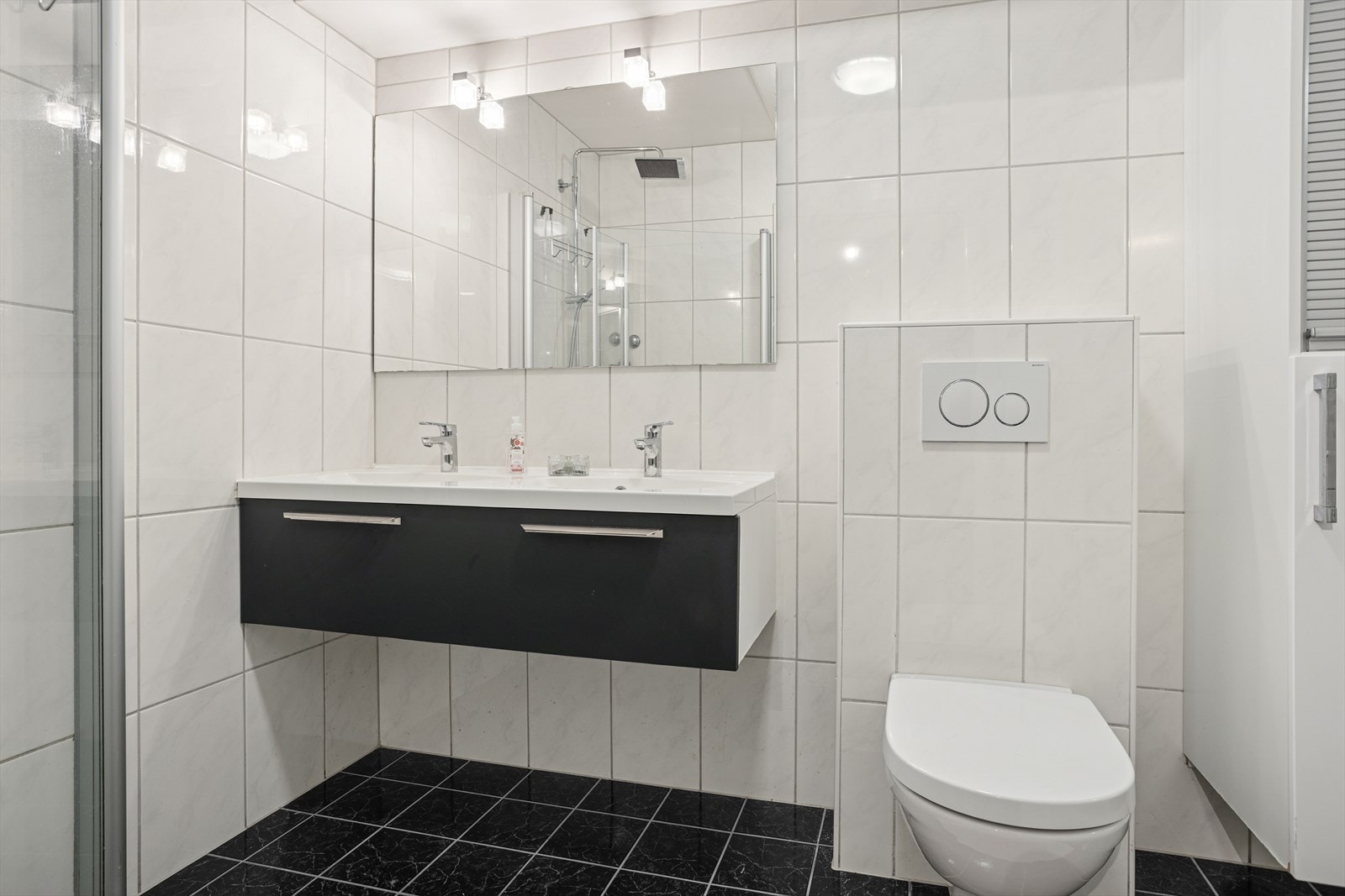 Helfliset bad med innredning bestående av innfellbart dusjhjørne, vegghengt toalett, vegghengt skap og dobbelservant med skuffeoppbevaring Galleribilde