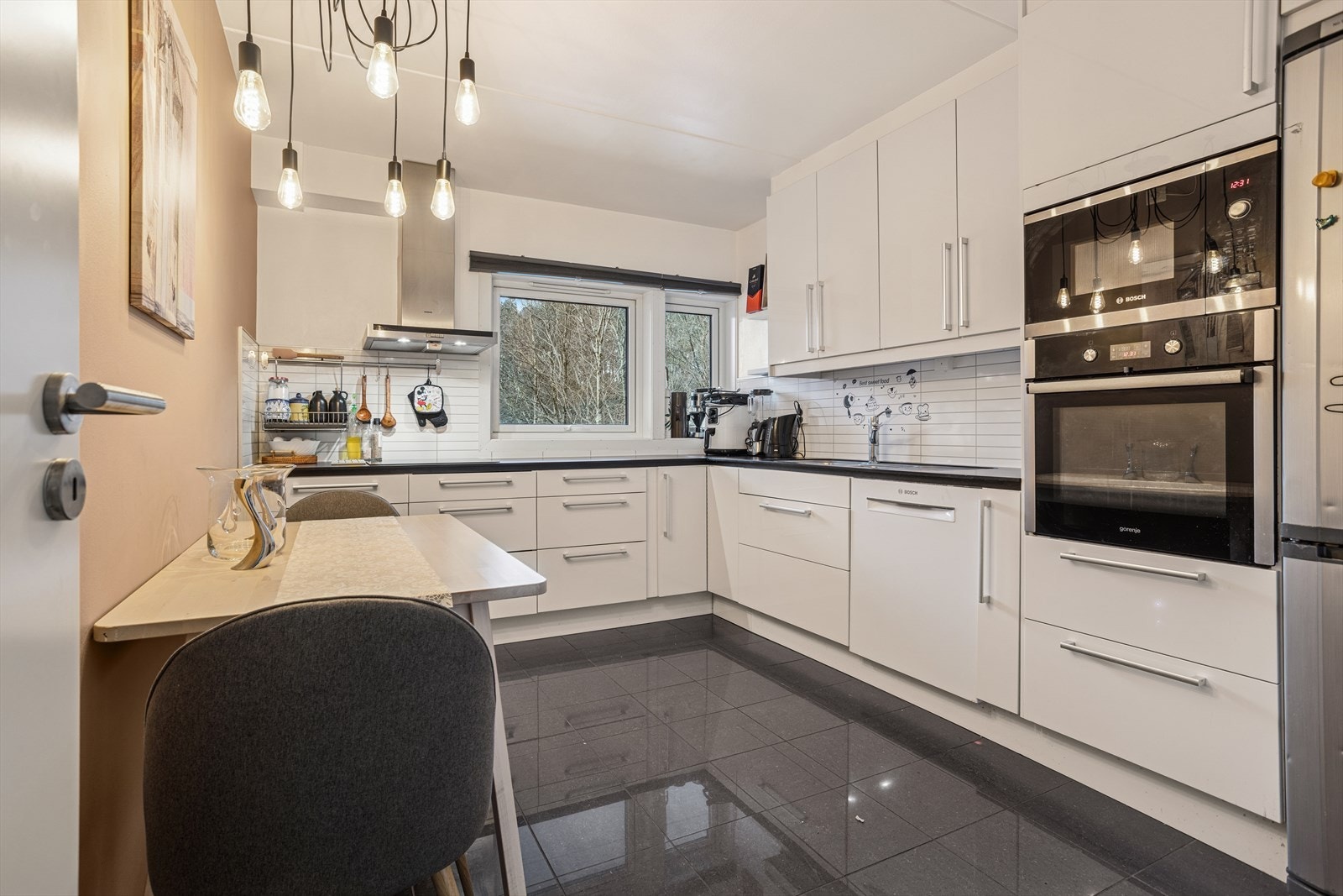 Kjøkkenet er fra Epoq og har slette hvite høyglansfronter, med en mørk laminat benkeplate Galleribilde