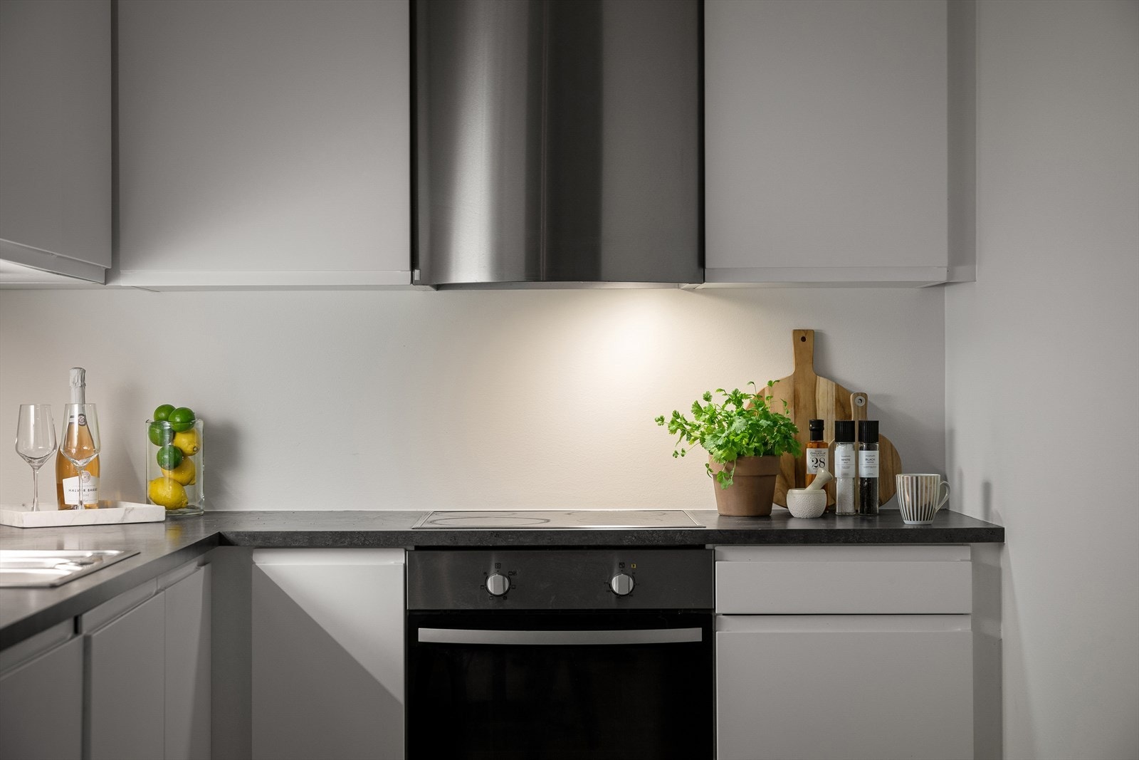 Detaljbilde av kjøkken som viser moderne overflater og gjennomtenkte løsninger. Kjøkkenet har mekanisk avtrekk over stekesonen. Galleribilde