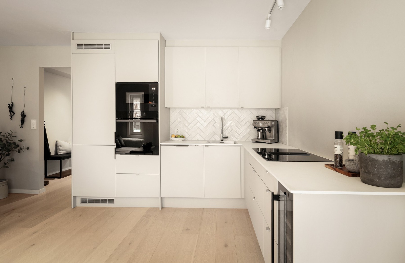 Et stilrent kjøkken med innredning fra Systemkjøkken og kompositt benkeplate. Integrerte hvitevarer med bl.a. vinskap i innredningen. Galleribilde