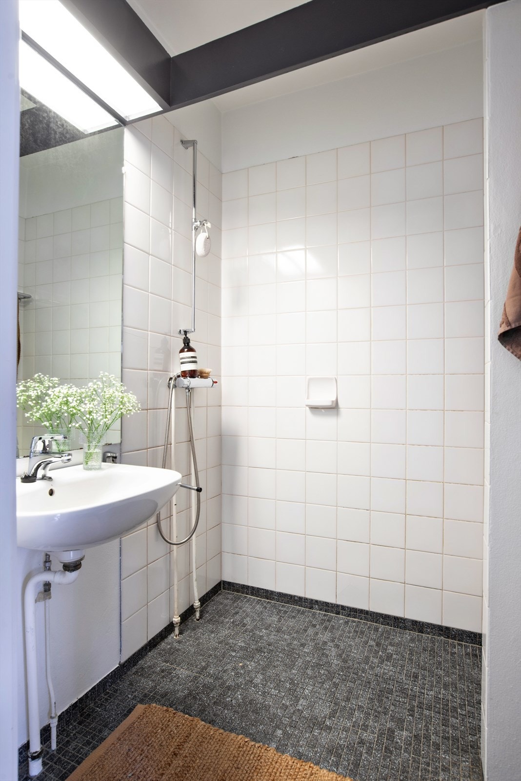 Flislagt bad utstyrt med gulvmontert toalett, dusjhjørne og servantskap med blandebatteri Galleribilde