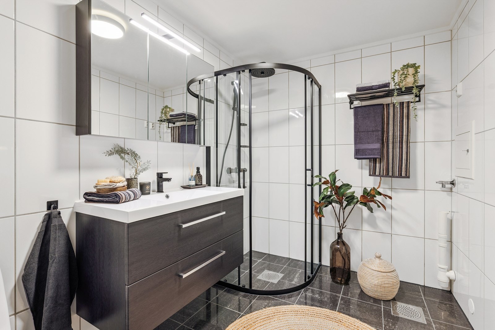 Lekkert flislagt bad fra 2008, fornyet med nytt og moderne servant- og speilskap og dusjhjørne i 2025. Galleribilde