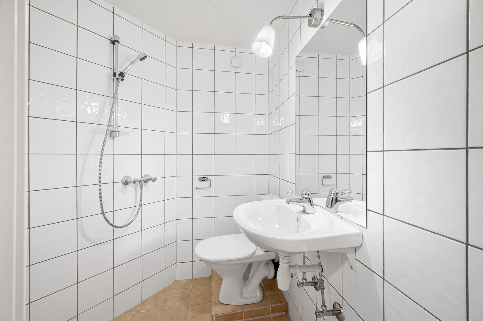 Flislagt bad i næringsdelen med dusj, servant og toalett. Galleribilde