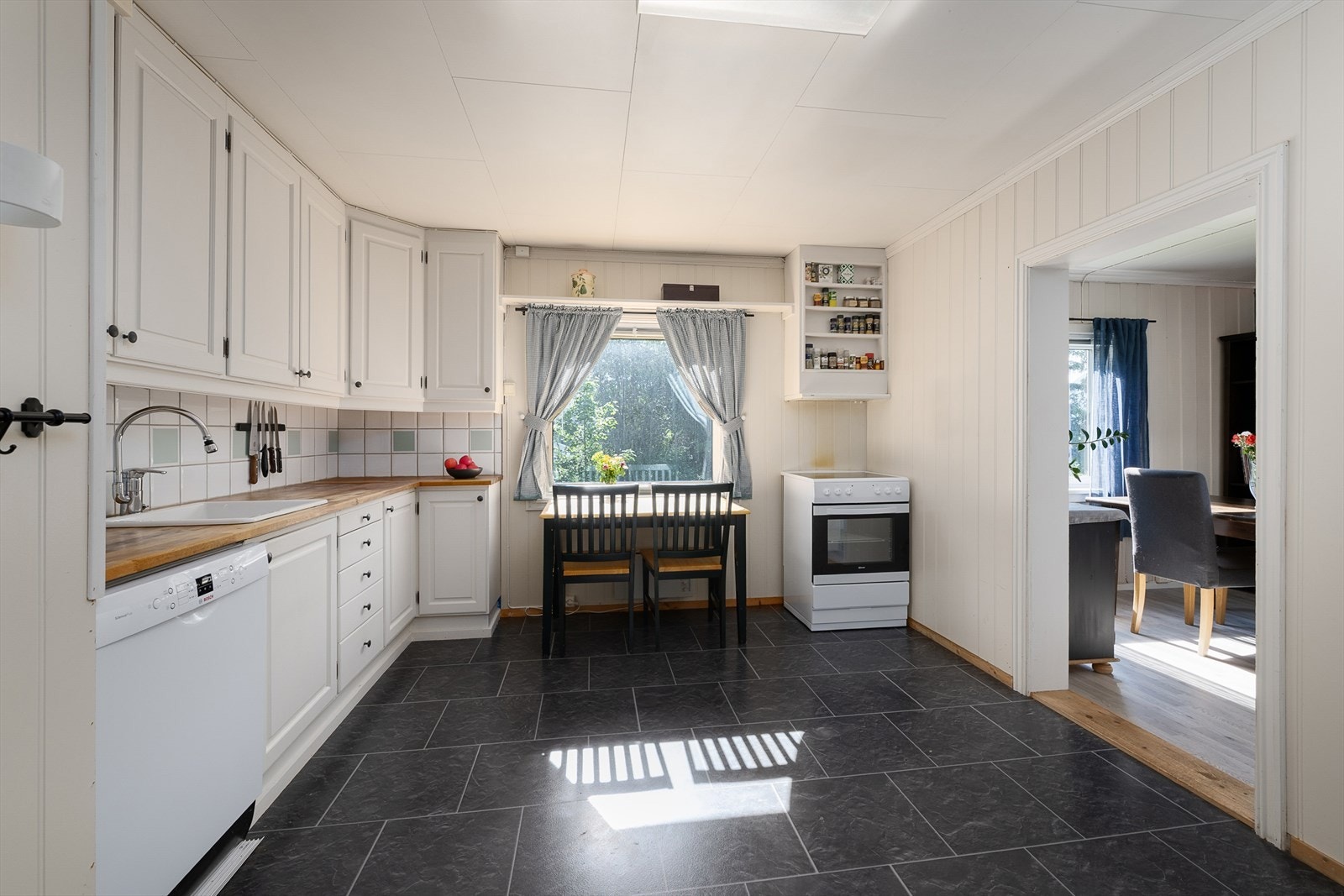 Lyst og romslig kjøkken med god skapplass og spiseplass ved vinduet Galleribilde