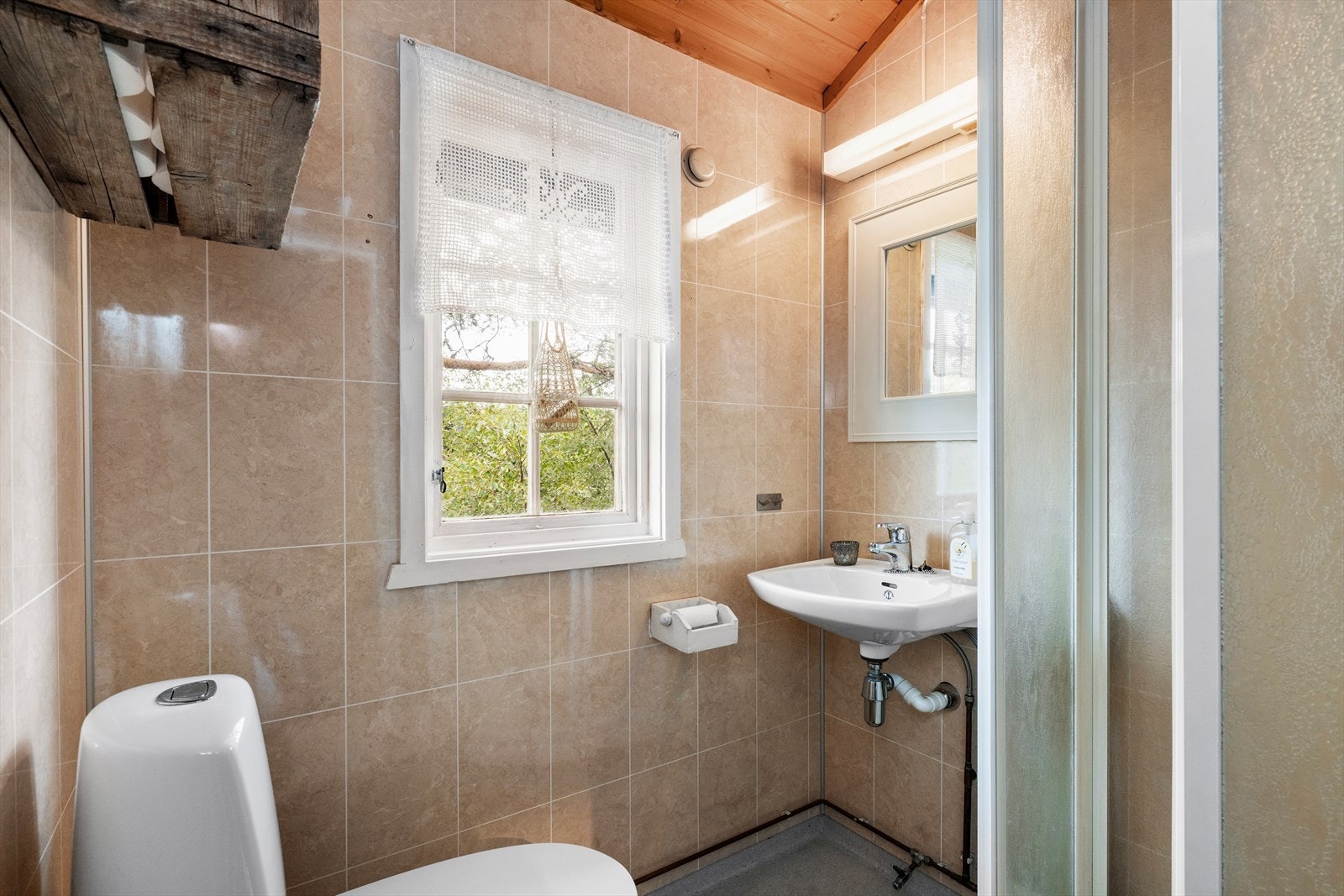 Badet har dusjkabinett, WC og servant med over belyst speil. Lufting mot yttervegg. Galleribilde