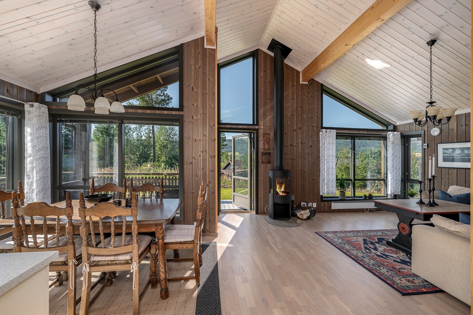 Stue og kjøkken med luftig takhøyde og store vindusflater Galleribilde