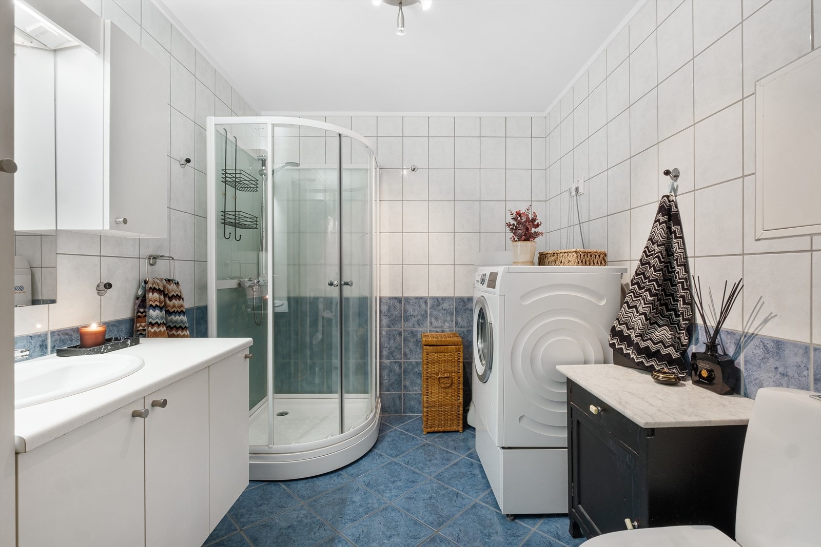 Badet er utstyrt med servant på innredning, veggskap og speil med lys. Det opplegg for vaskemaskin. Galleribilde