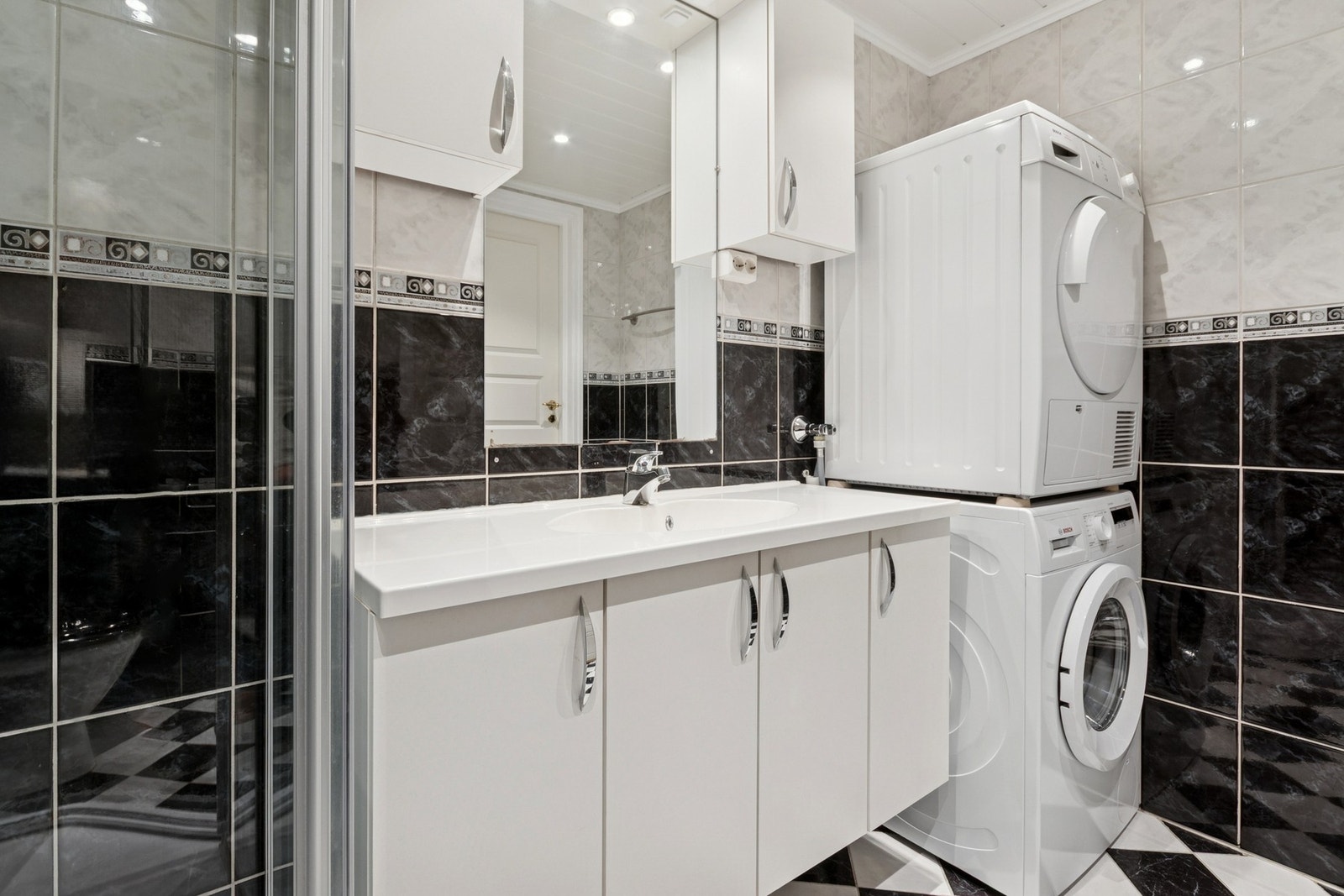 Badet er innredet med nedfelt servant, toalett, dusjkabinett og opplegg for vaskemaskin. Galleribilde