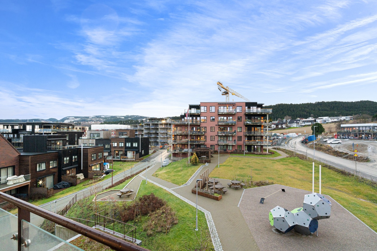 Utsikt mot grønne fellesarealer med sittegrupper og internstier. Galleribilde