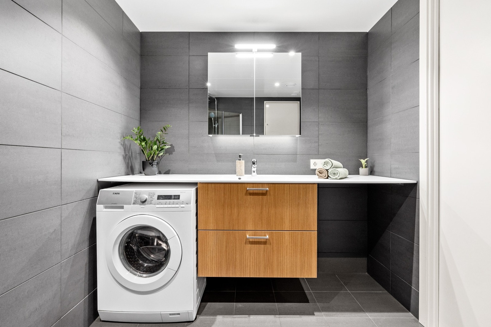 Badet er innredet med vegghengt toalett, dusjhjørne med innfellbare dører, servant og speilskap med overbelysning Galleribilde