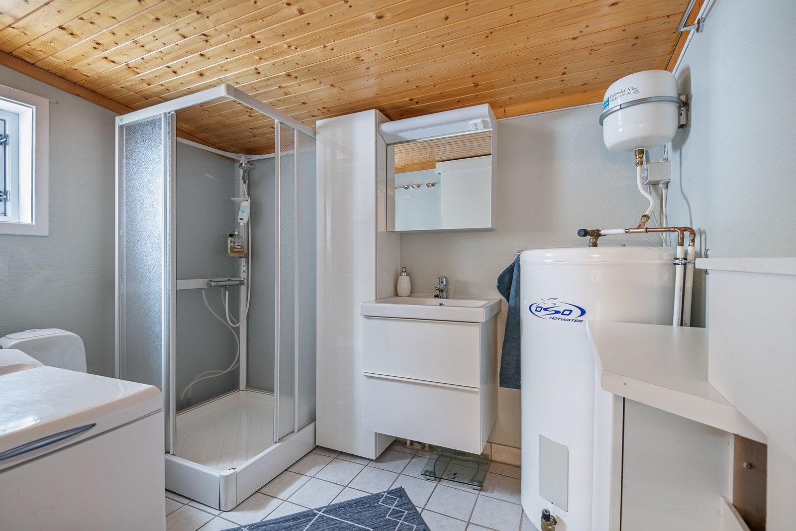 Badet inneholder servant med underskap og speil med tilhørende belysning. Videre inneholder baderommet dusjkabinett og gulvmontert toalett. Galleribilde