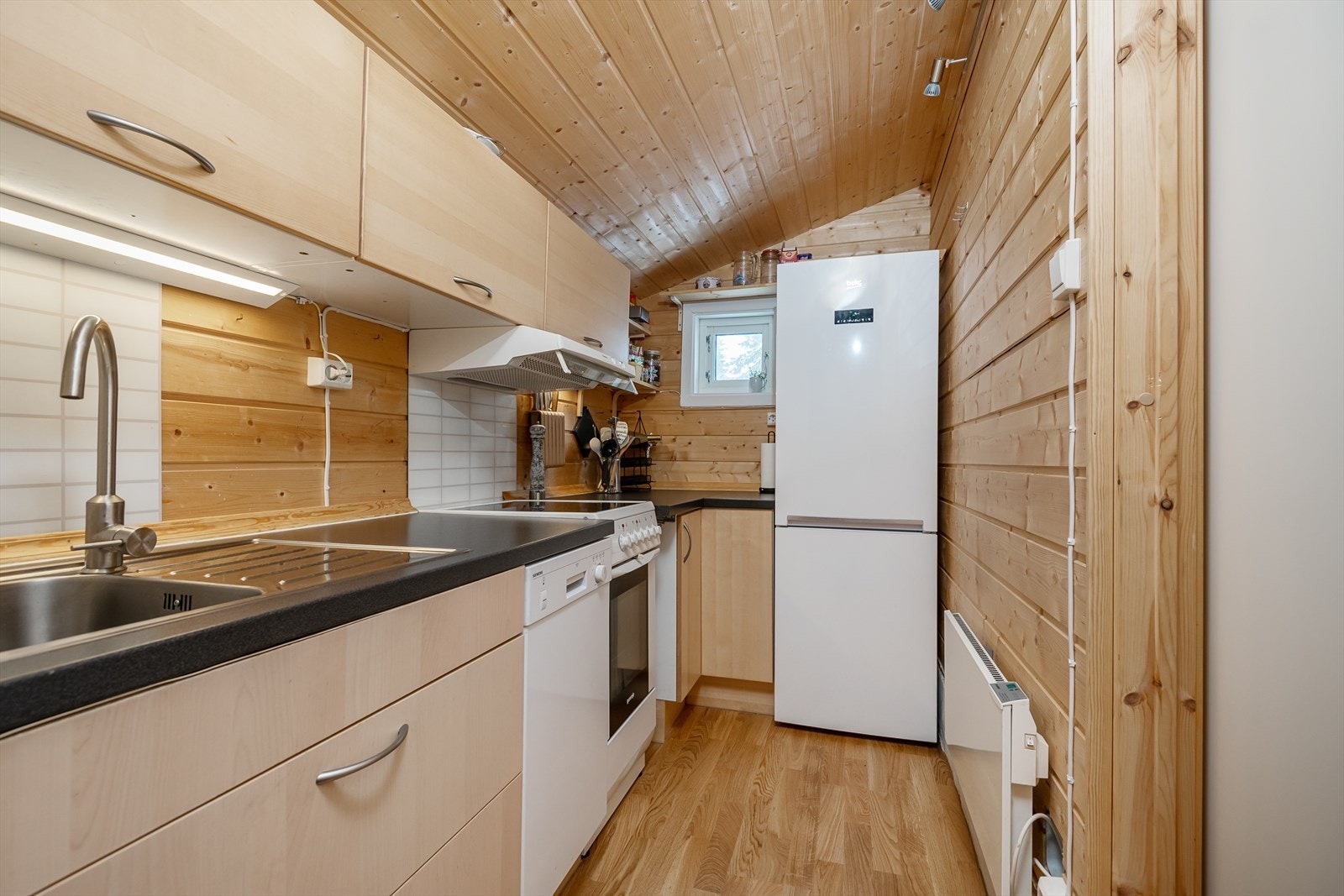 Hytta har et kjøkken med lys kjøkkeninnredning med laminerte skrog. Galleribilde