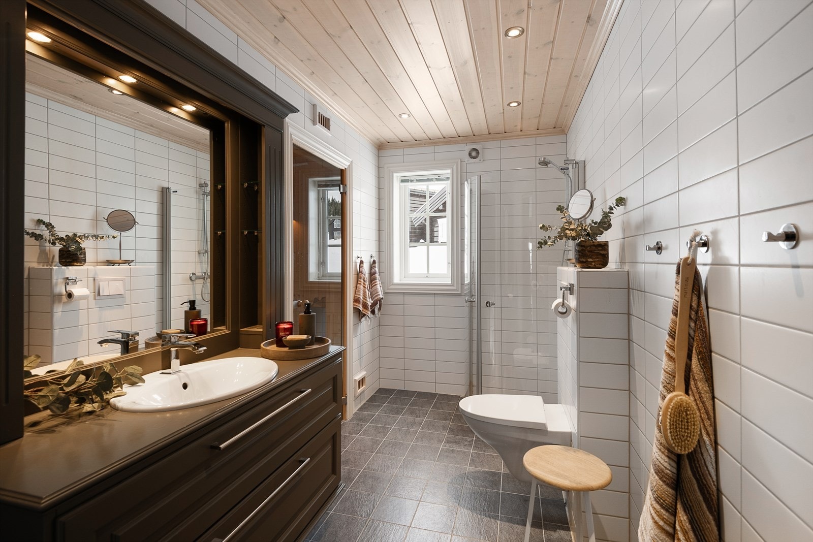 Hovedbadet er utstyrt med vegghengt klosett, dusjhjørne med dører og en servantinnredning med skuffer. Galleribilde