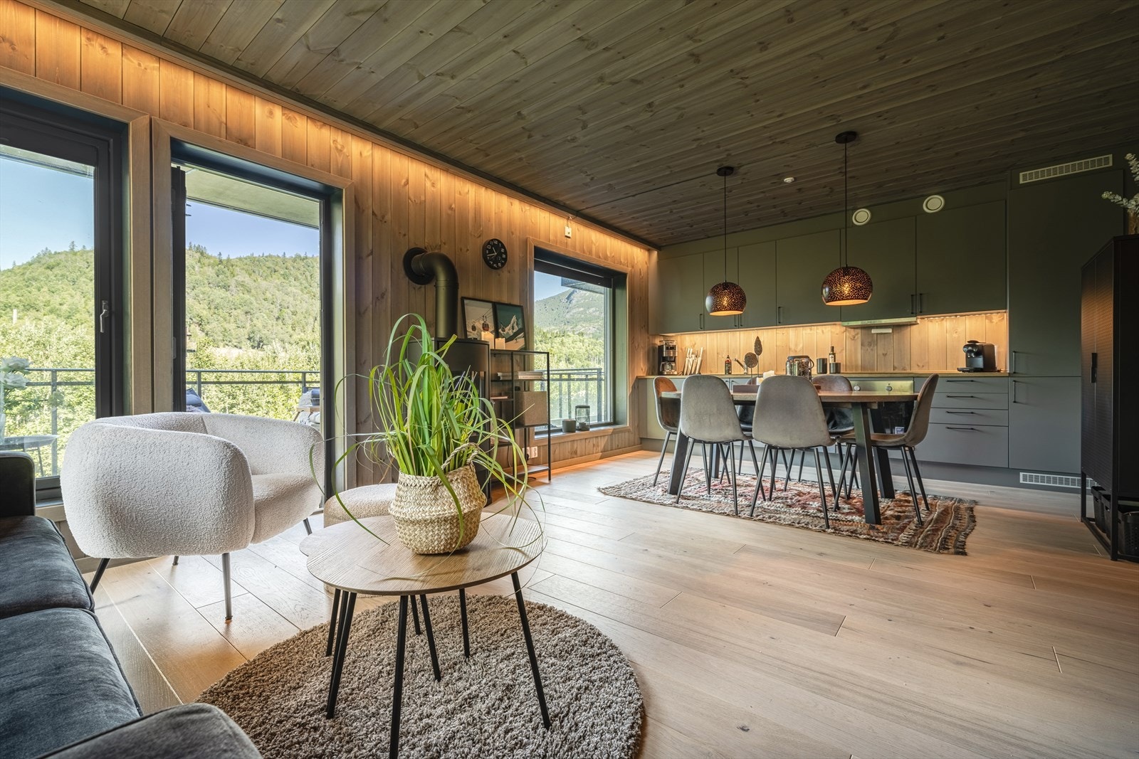 Åpen stue/kjøkkenløsning med store vindusflater og utgang til terrasse. Galleribilde