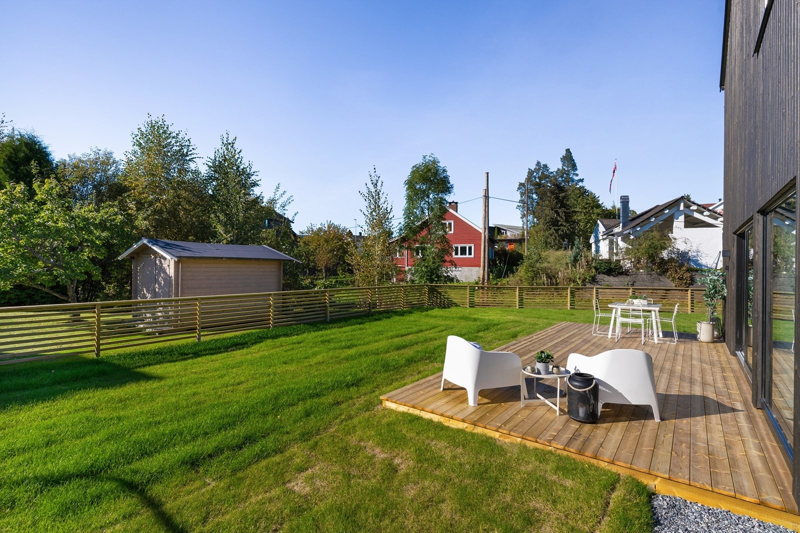 Boligen er også ferdig opparbeidet utendørs, her med markterrasse utenfor stuedelen, og med ferdig gressplen og inngjerding i front og på siden av boligen. Galleribilde