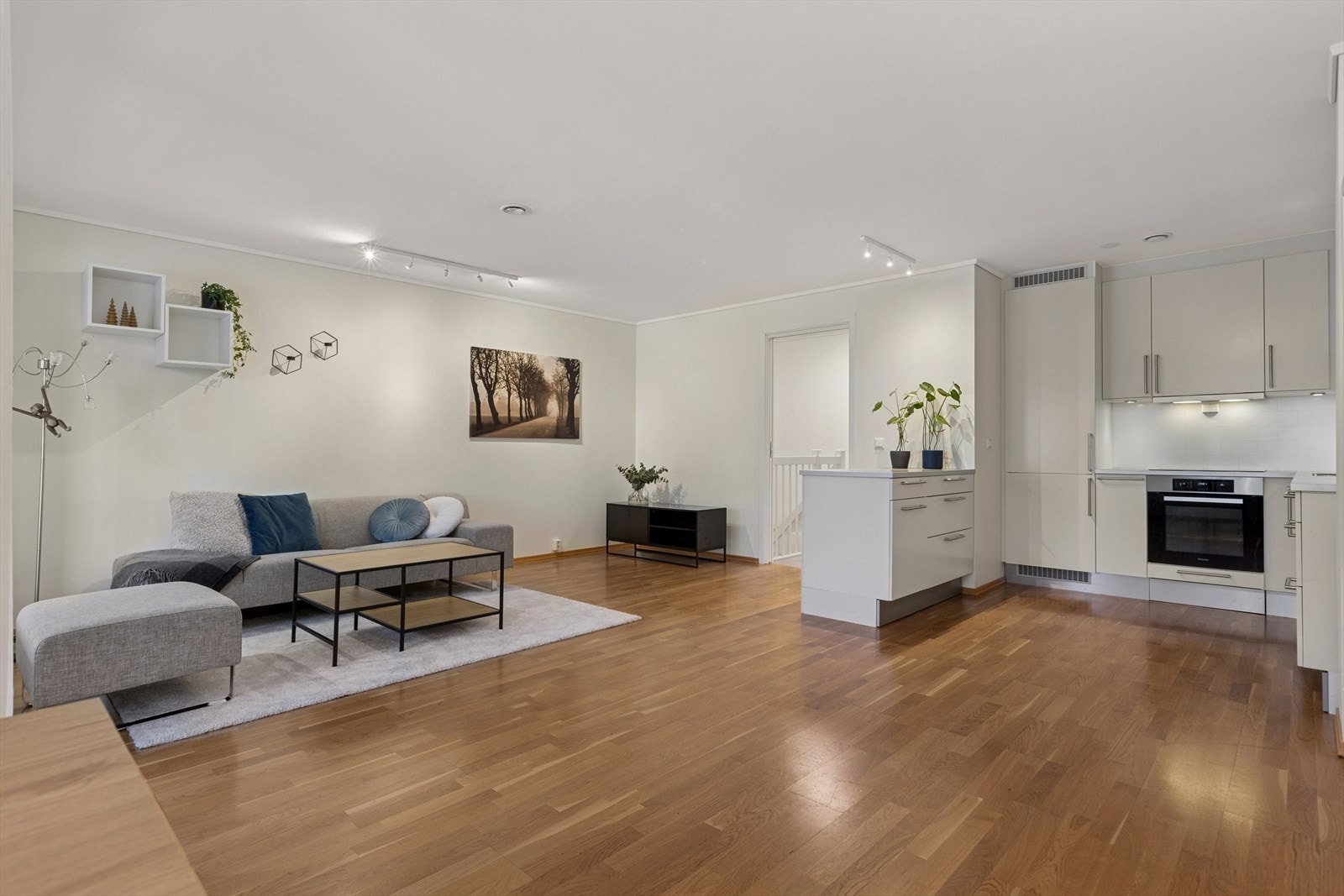 Lyst parkettgulv strekker seg fra stuen til kjøkkenet og gir en helhetlig følelse. Galleribilde