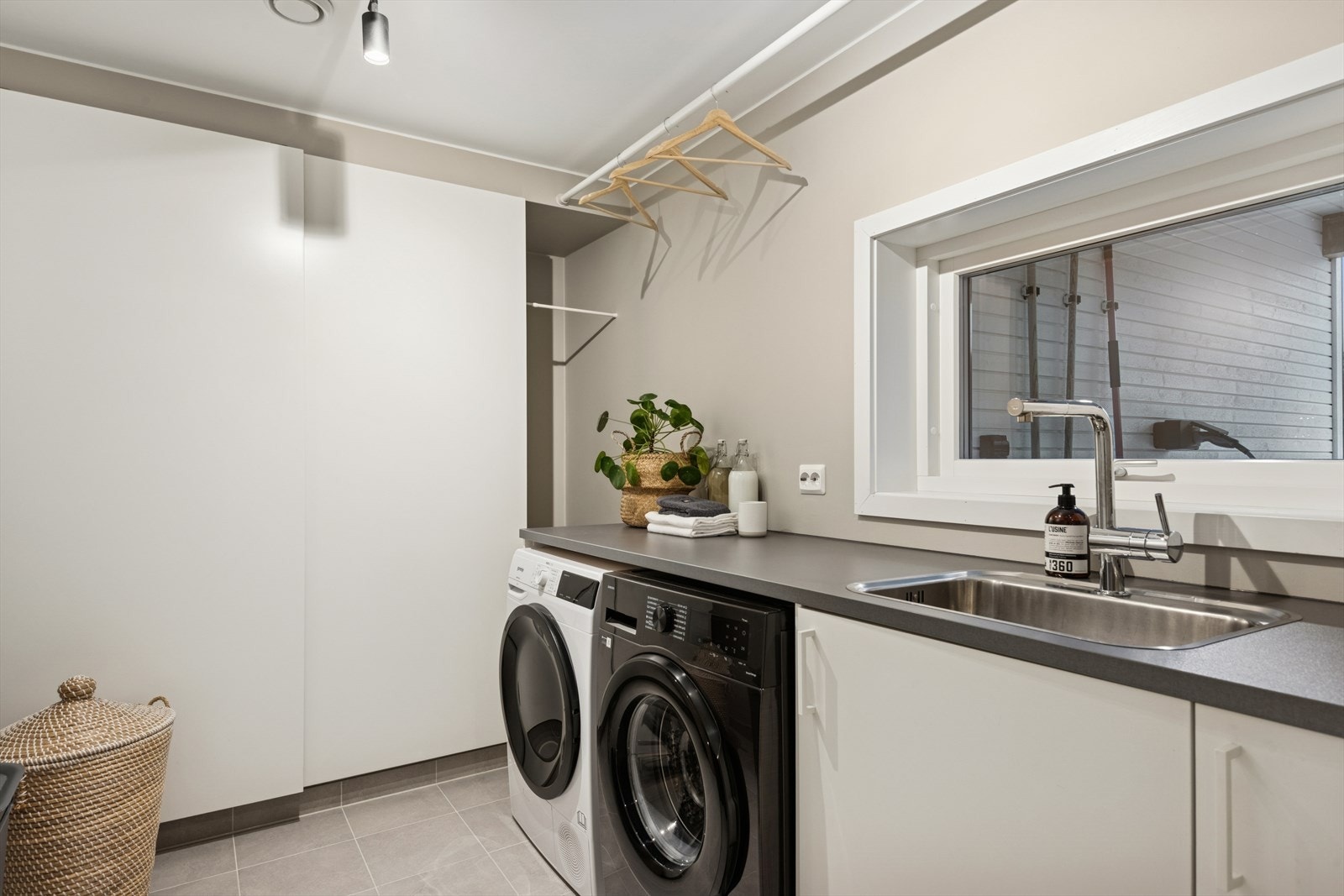 Praktisk vaskerom med flislagt gulv og gulvvarme, malte vegger og malt tak. Galleribilde