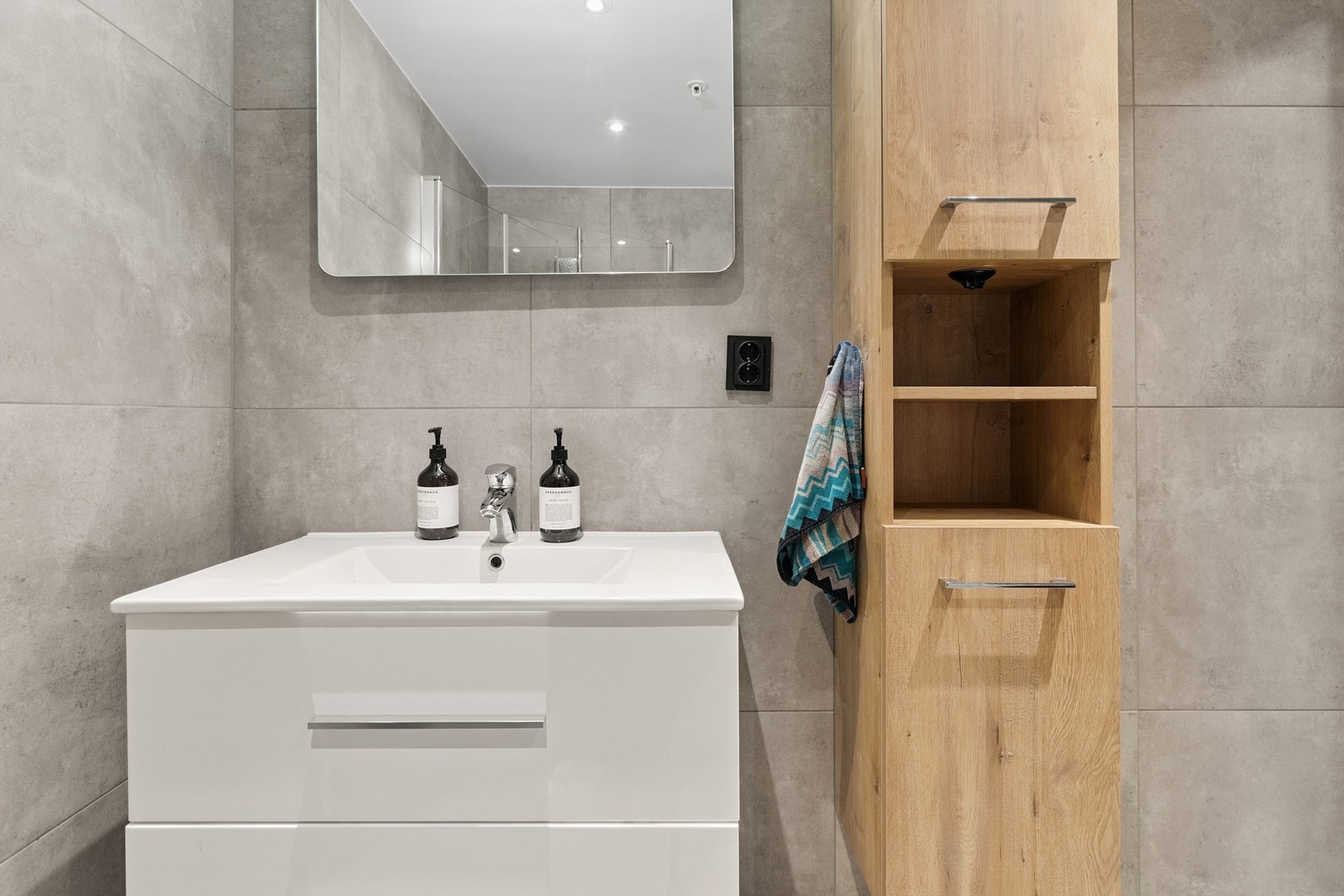 Baderomsinnredning med servant og høyskap gir gode oppbevaringsmuligheter. Galleribilde