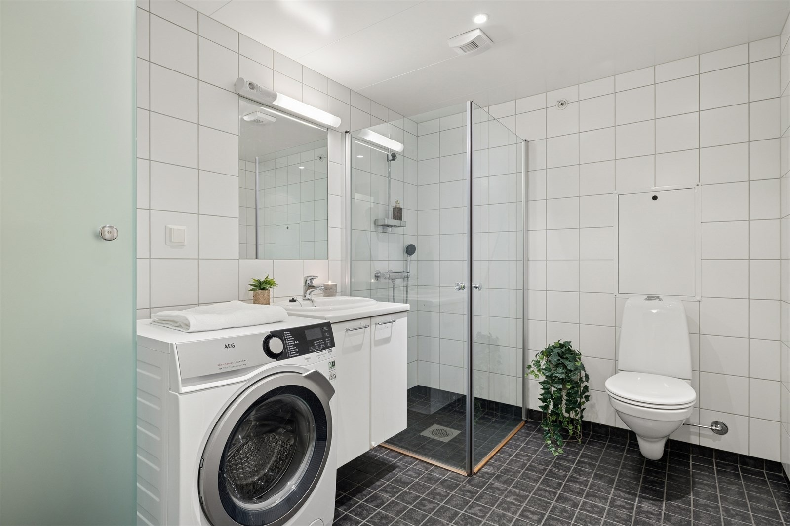 Baderommet er innredet med klassisk baderomsinnredning, samt praktisk opplegg for vaskemaskin. Galleribilde