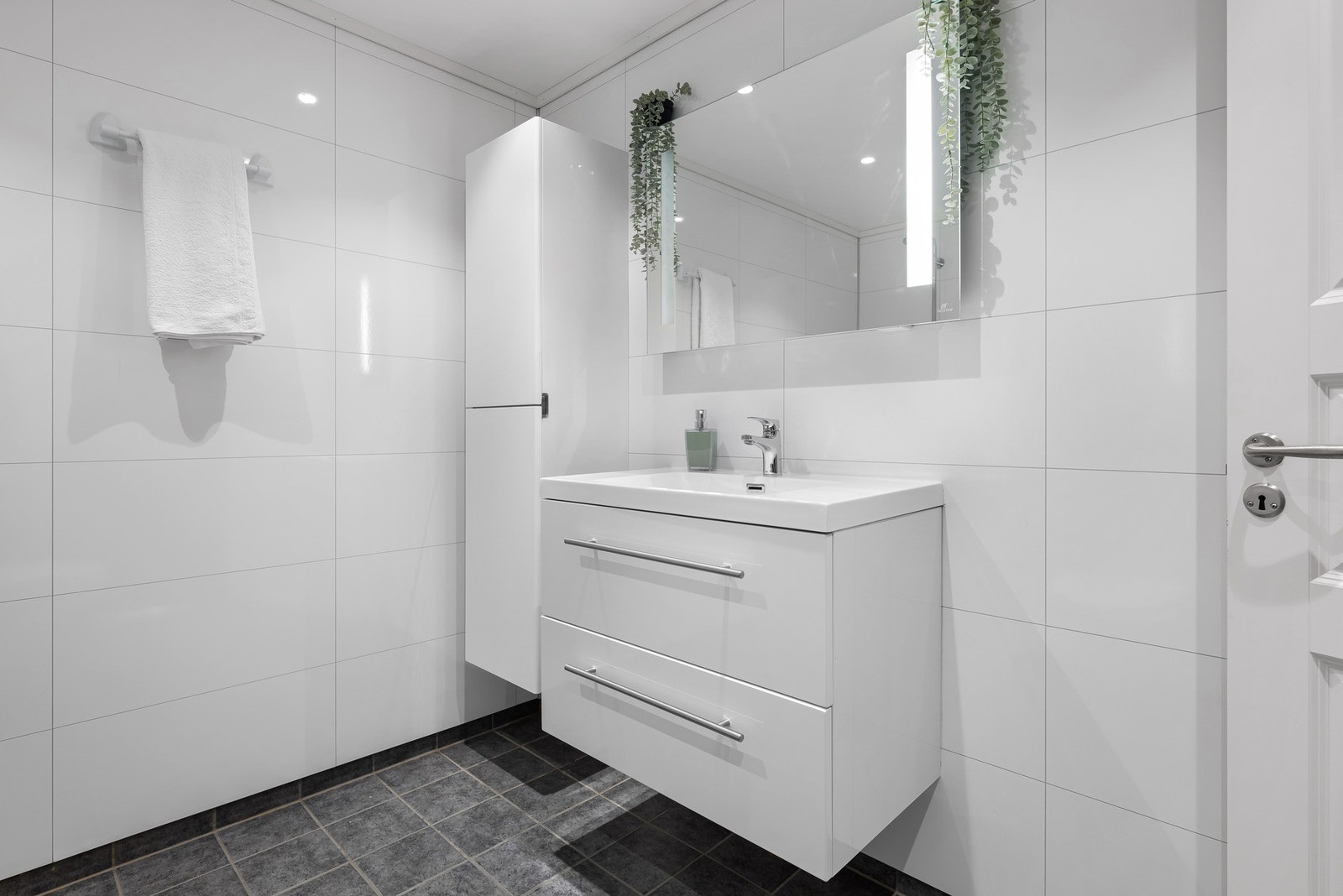 Baderomsinnredningen består av vegghengt toalett, helstøpt servant, skuffer under servant med slette fronter, og dusjgarnityr. Galleribilde