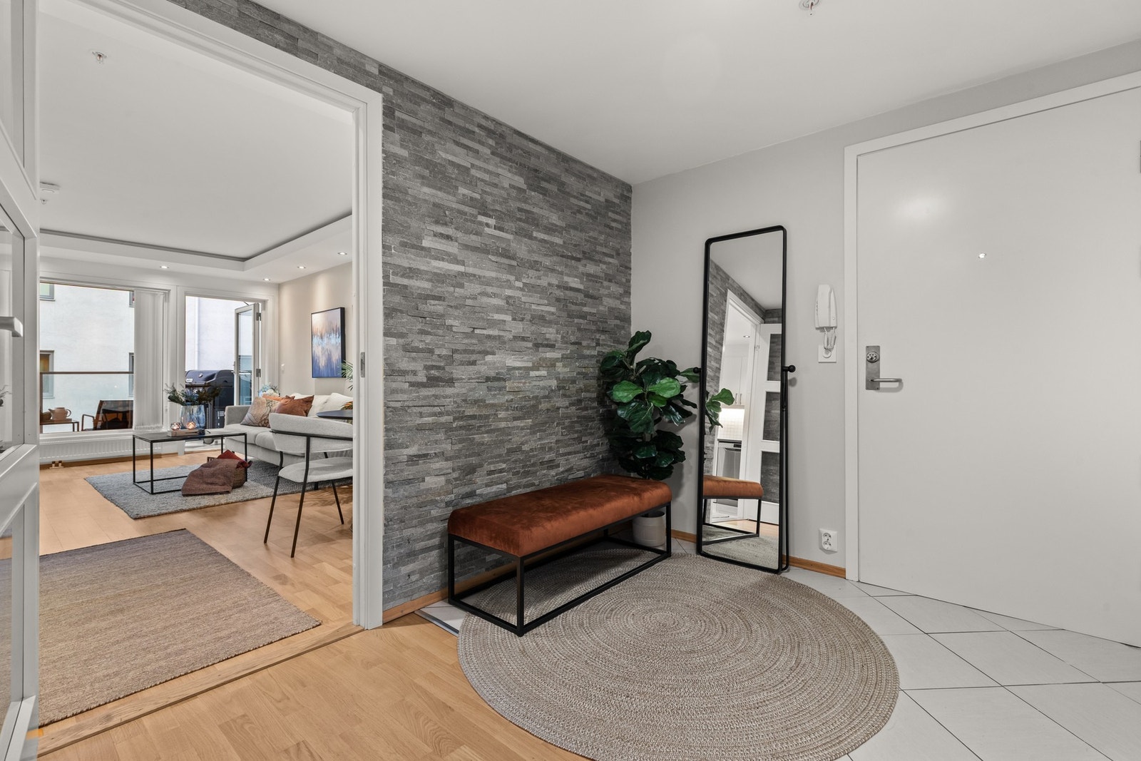 Romslig og innbydende entré med flislagt gulv og kontrastvegg med steinfliser. Galleribilde