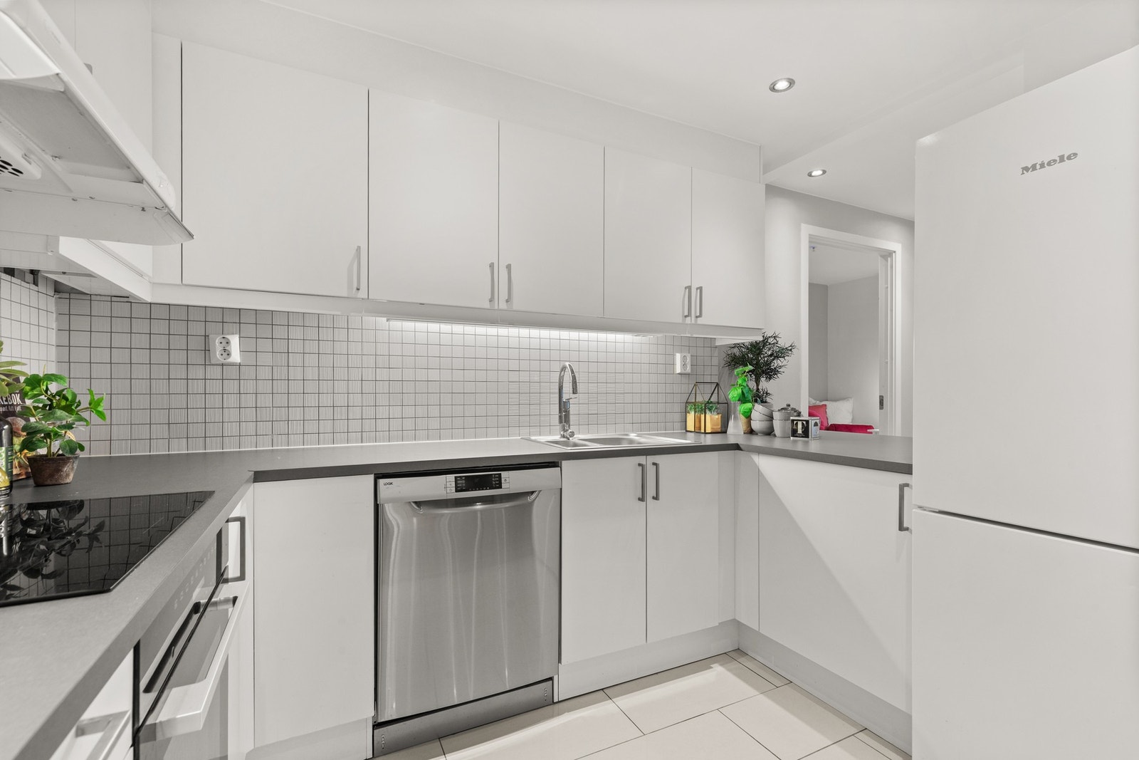 Integrerte hvitevarer bestående av stekeovn, induksjonstopp, oppvaskmaskin samt nisje for frittstående kjøl/frys. Galleribilde