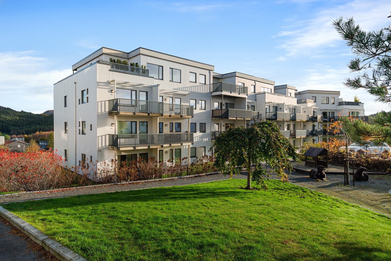 Tomten er pent opparbeidet med asfalt, støpt platting og beplantning. Dette gir et ryddig og innbydende uteområde. Galleribilde