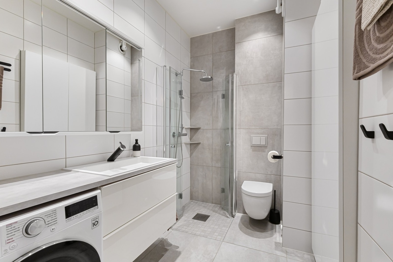 Stort og flislagt baderom med gulvvarme, downlights og vegghengt toalett Galleribilde