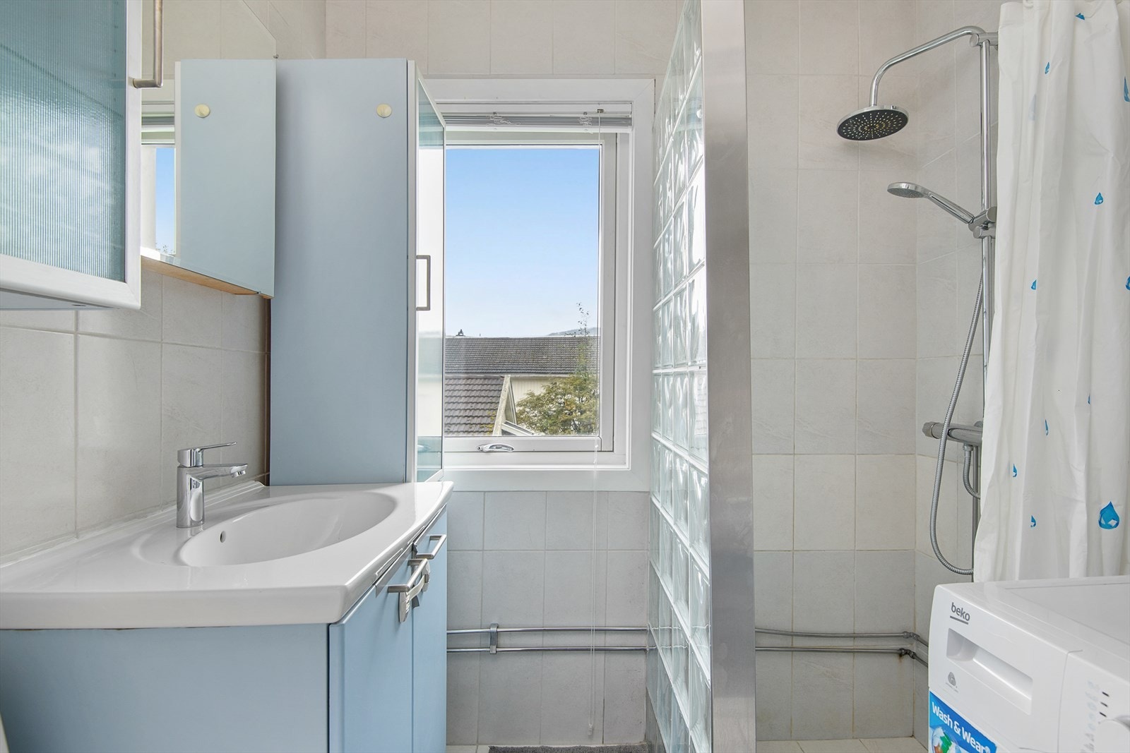 Flislagt baderom med dusjsone og opplegg til vaskemaskin Galleribilde