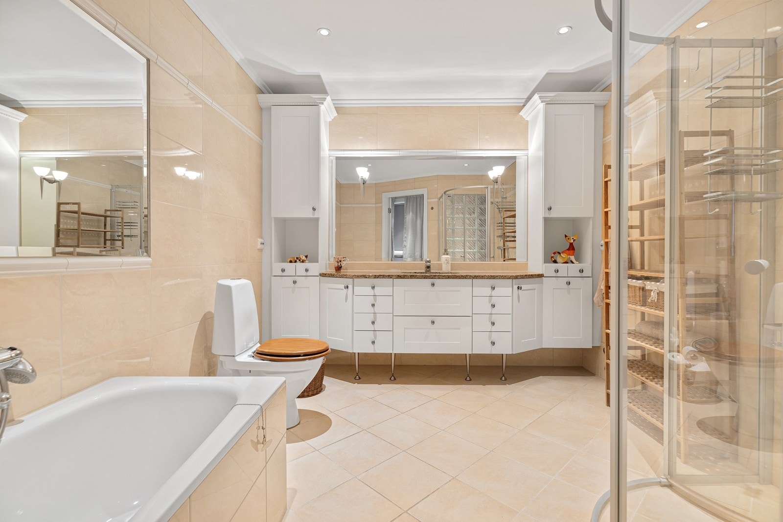 Romslig og flott flislagt bad. Servantinnredning med steinplate, innfliset badekar og speil, toalett og dusjhjørne Galleribilde