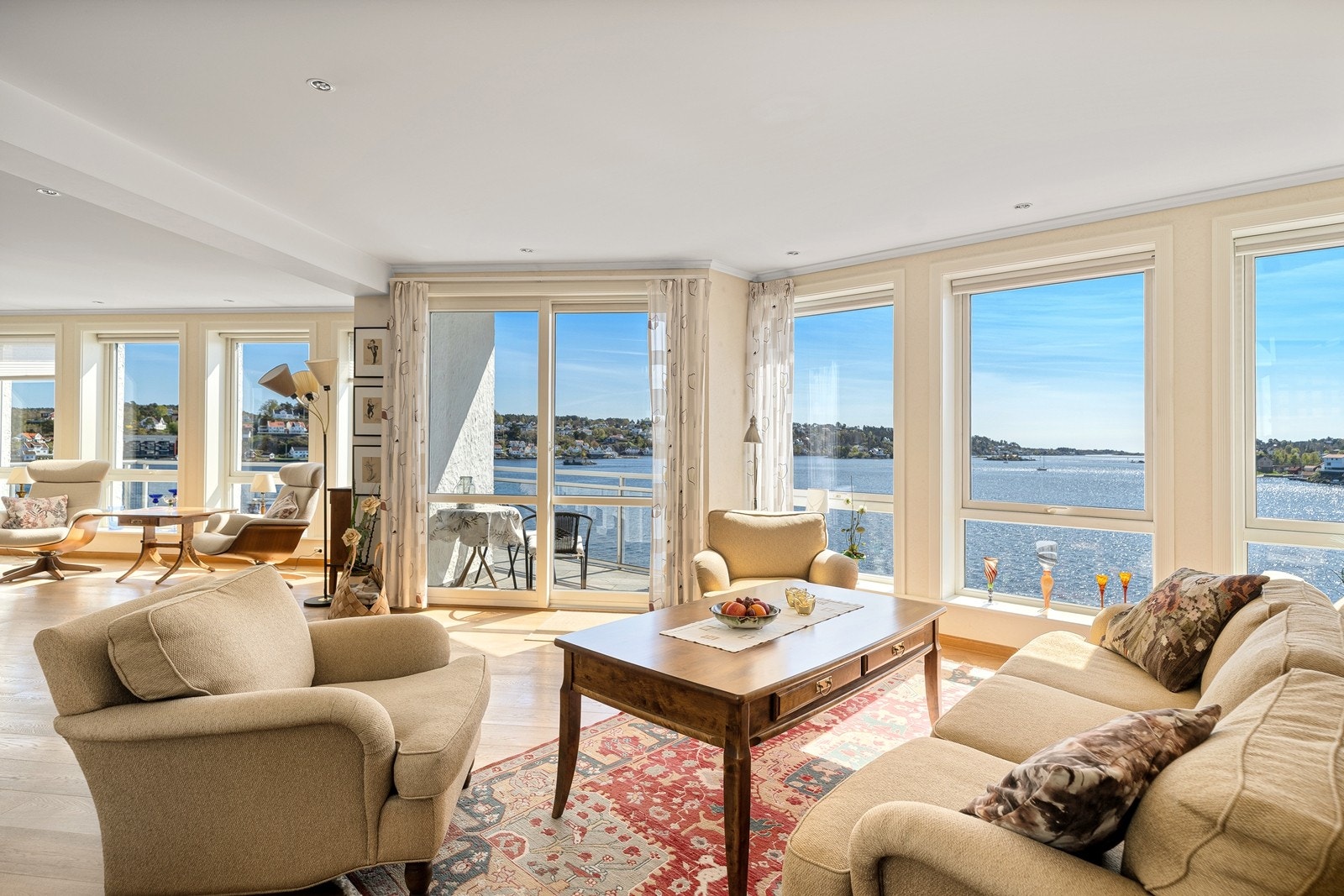 Romslig og lys stue med store vinduer som strekker seg over hele fronten av rommet. Dette fremhever den vakre utsikten og fyller rommet med naturlig lys. Galleribilde