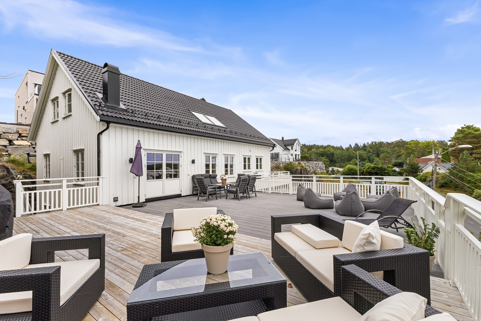 Stor og solrik veranda som innbyr til et rikt liv ute - med rikelig plass både til loungegrupper, spisebord og blomstrende krukker Galleribilde