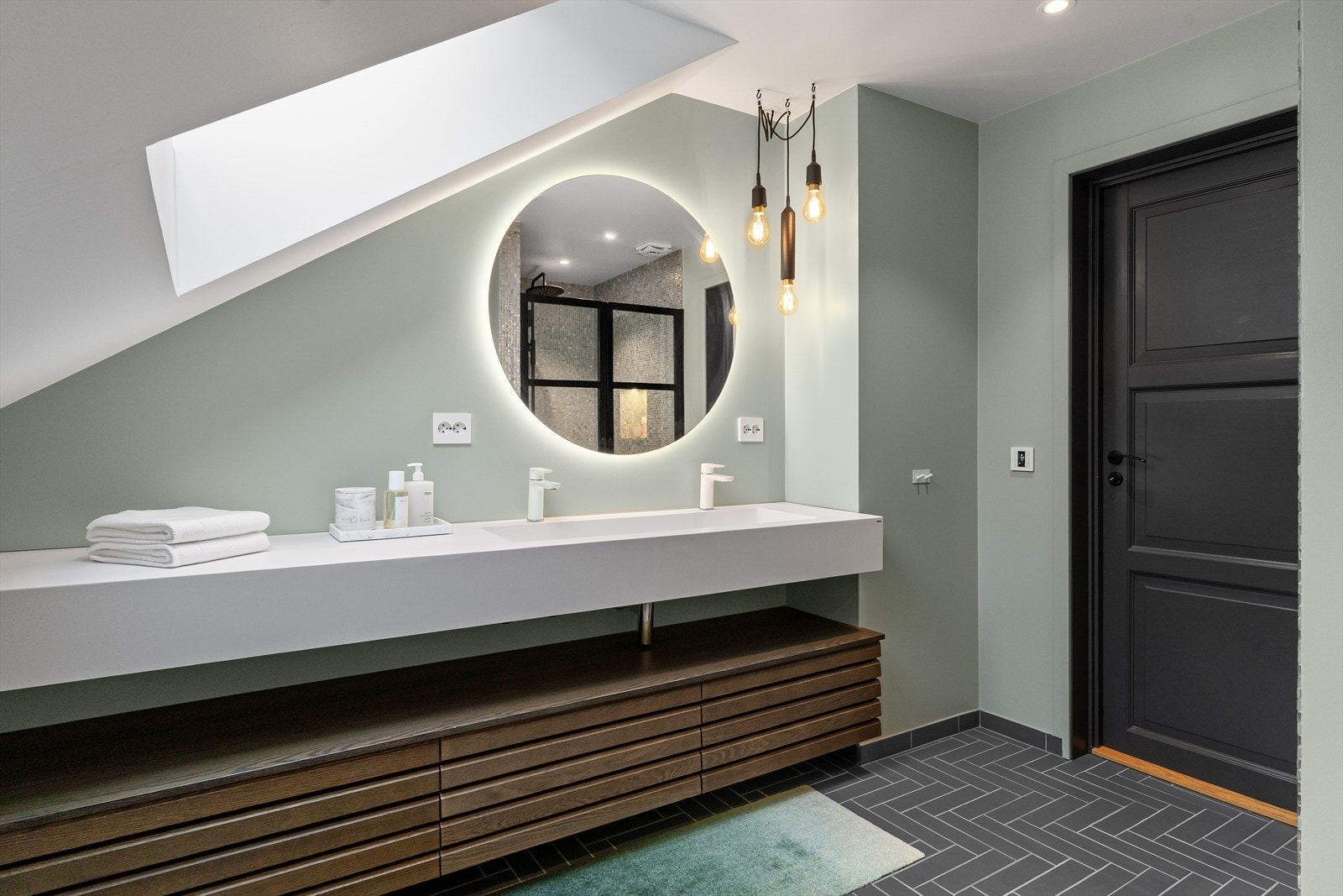 Badet inneholder vegghengt toalett, dusjhjørne og dobbeltvask. Galleribilde