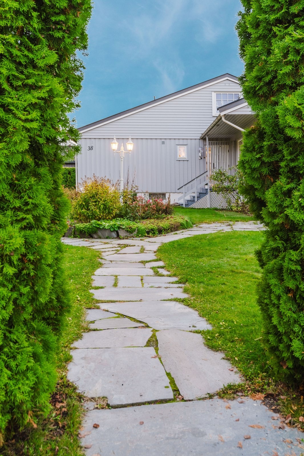 Du ønskes velkommen via en sjarmerende steinlagt gangvei omgitt av velholdt hage. Galleribilde