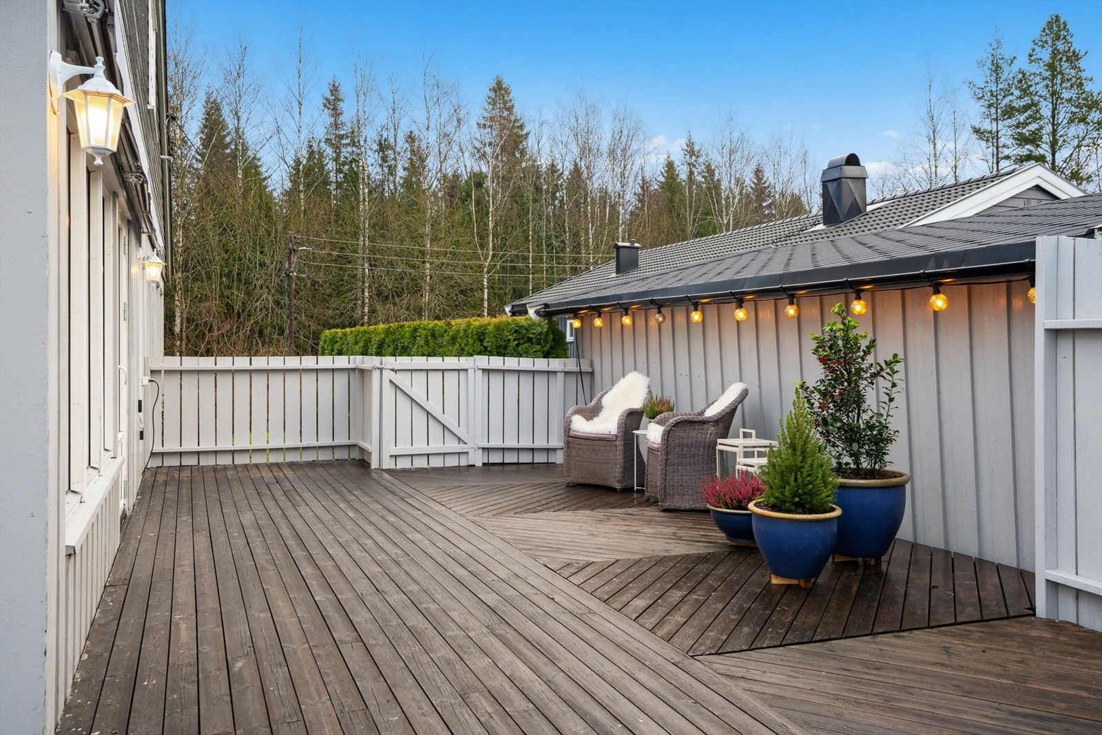 Terrassen er omgitt av et hvitmalt stakittgjerde som gir avskjerming og privatliv. Galleribilde