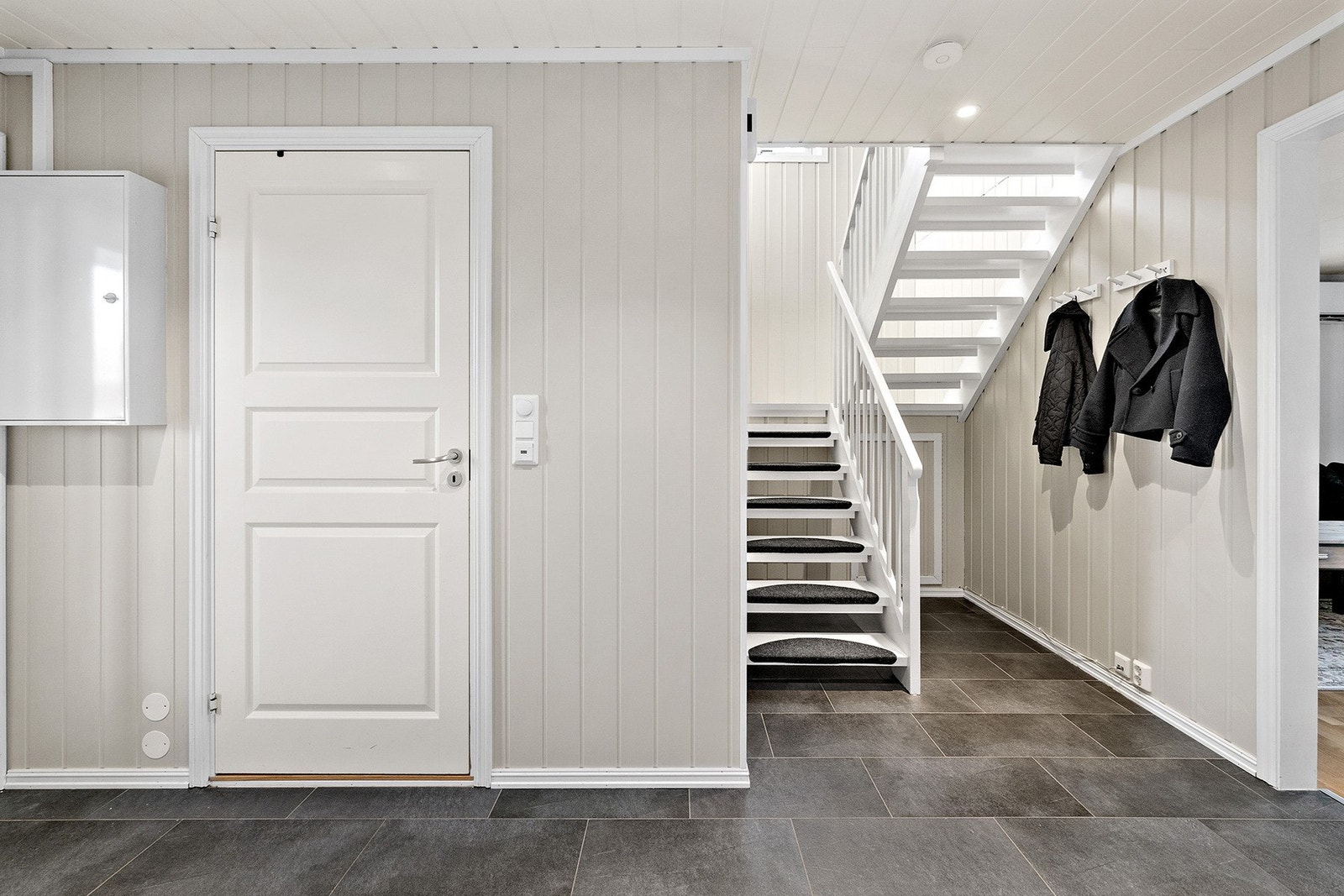 En hvit tretrapp binder etasjene elegant sammen og skaper en fin flyt gjennom boligen. Galleribilde