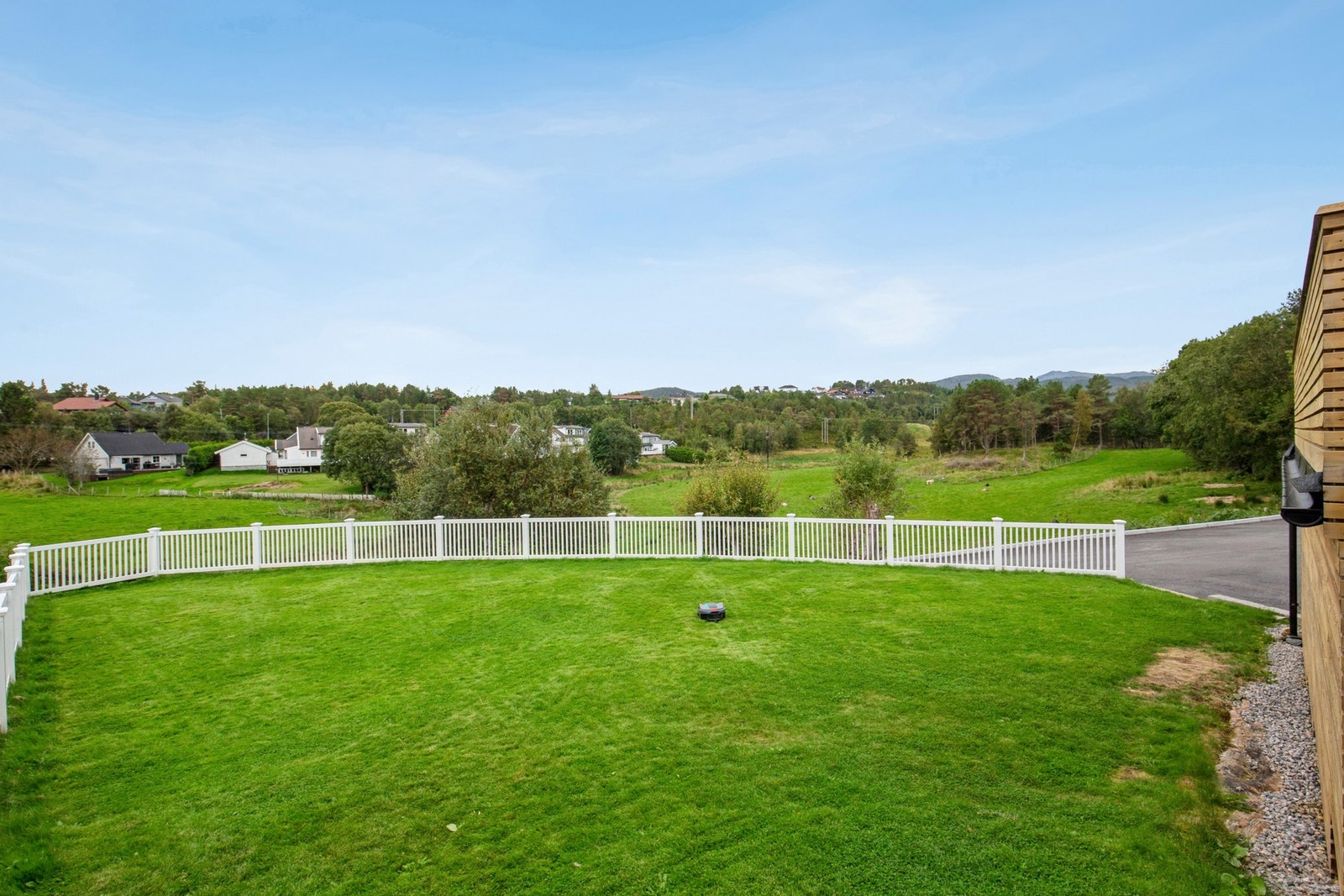 Tomten er pent opparbeidet med gårdsplass, plen og prydebusker Galleribilde
